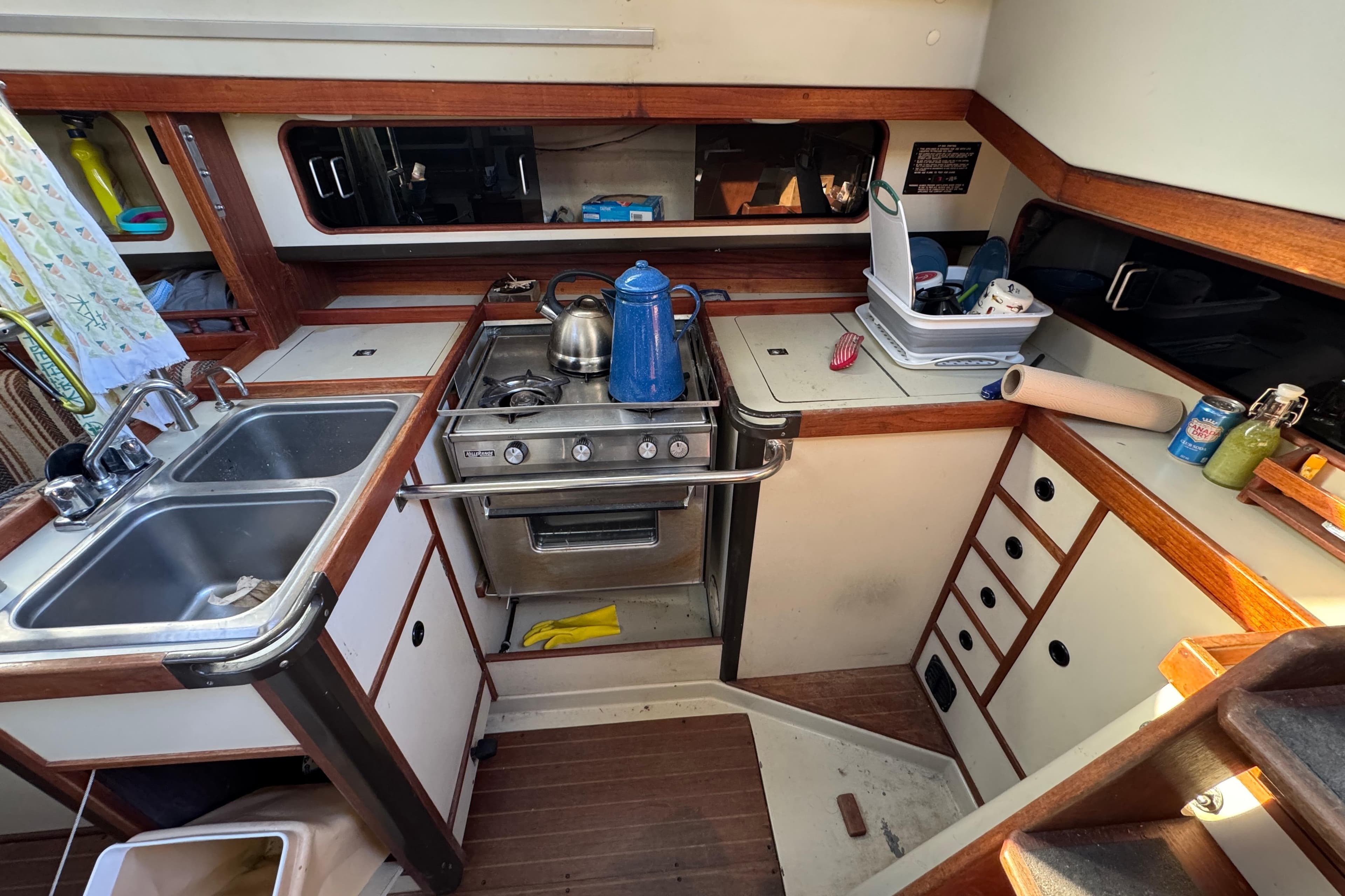 1982 C&C 37 yacht kitchen with stove, sink, and wooden cabinetry.