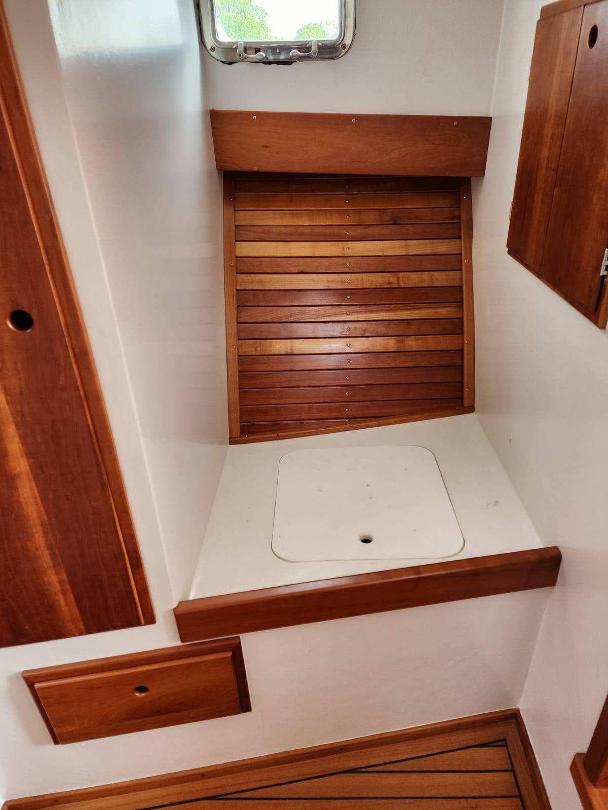 Interior of 2016 Custom Broad Creek 32 Downeast boat with wooden accents and storage compartments.