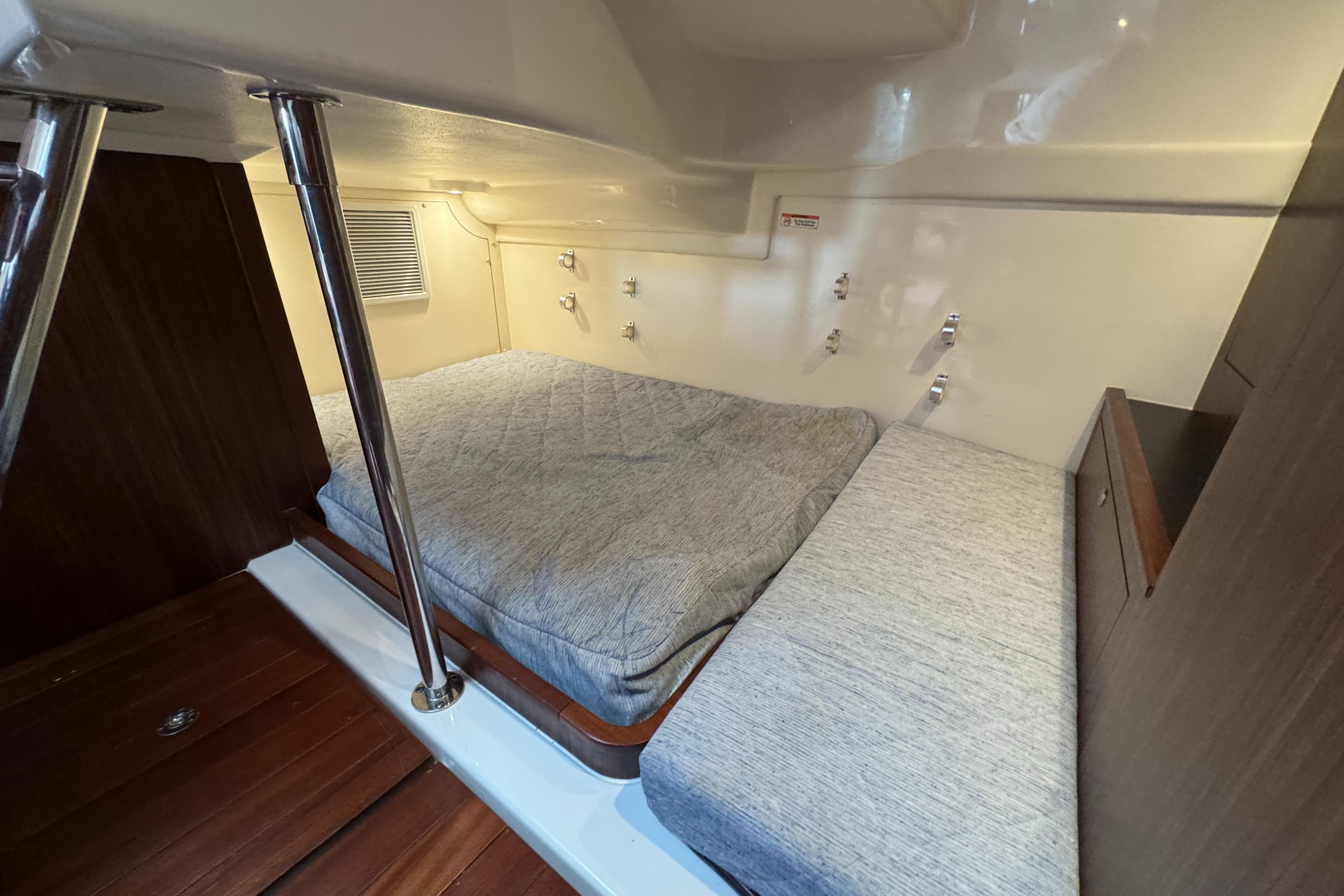 2019 Pursuit OS 355 Offshore cabin interior with cozy bedding and wooden accents.