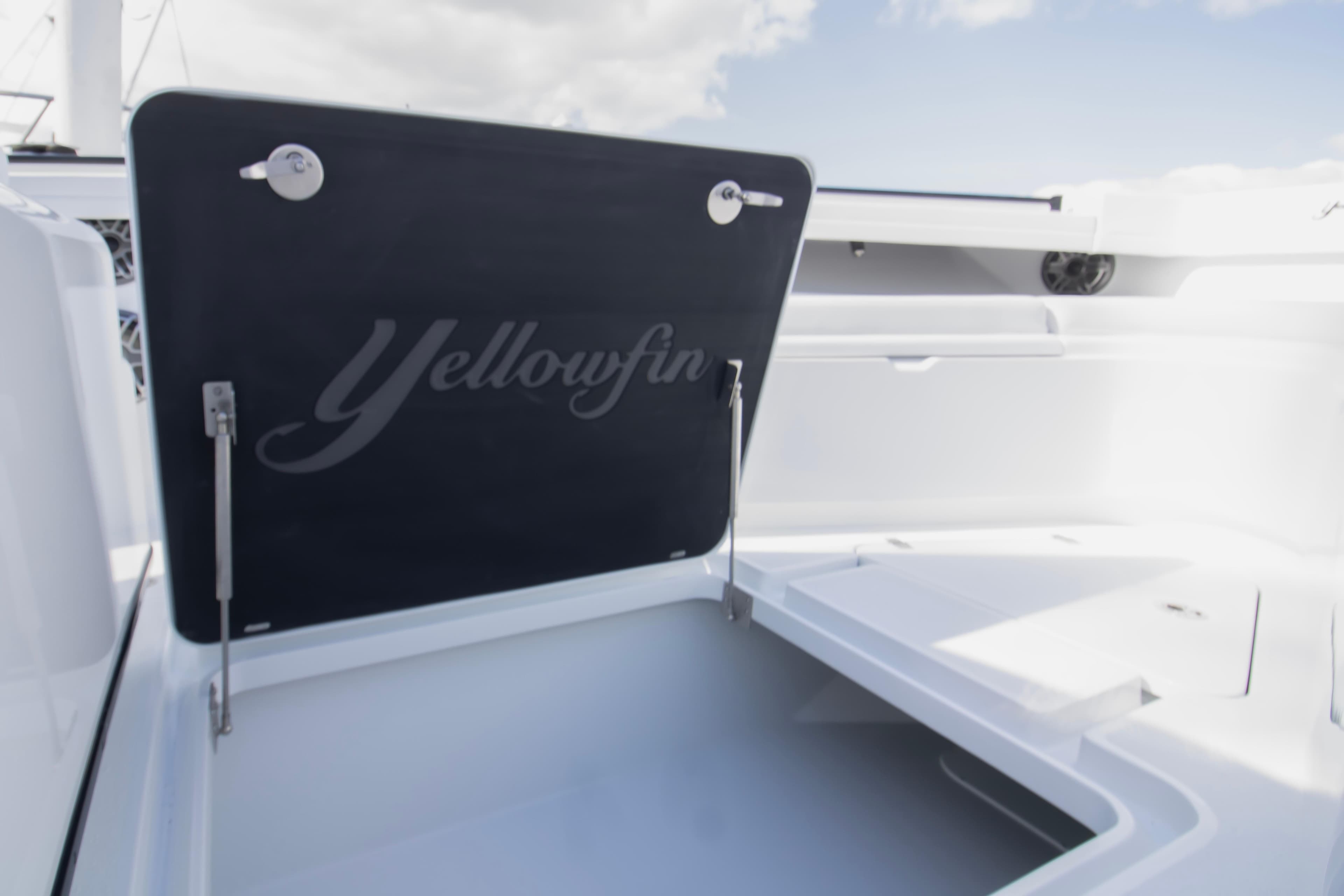 2026 Yellowfin 42 Offshore boat storage compartment with open lid under a clear sky.