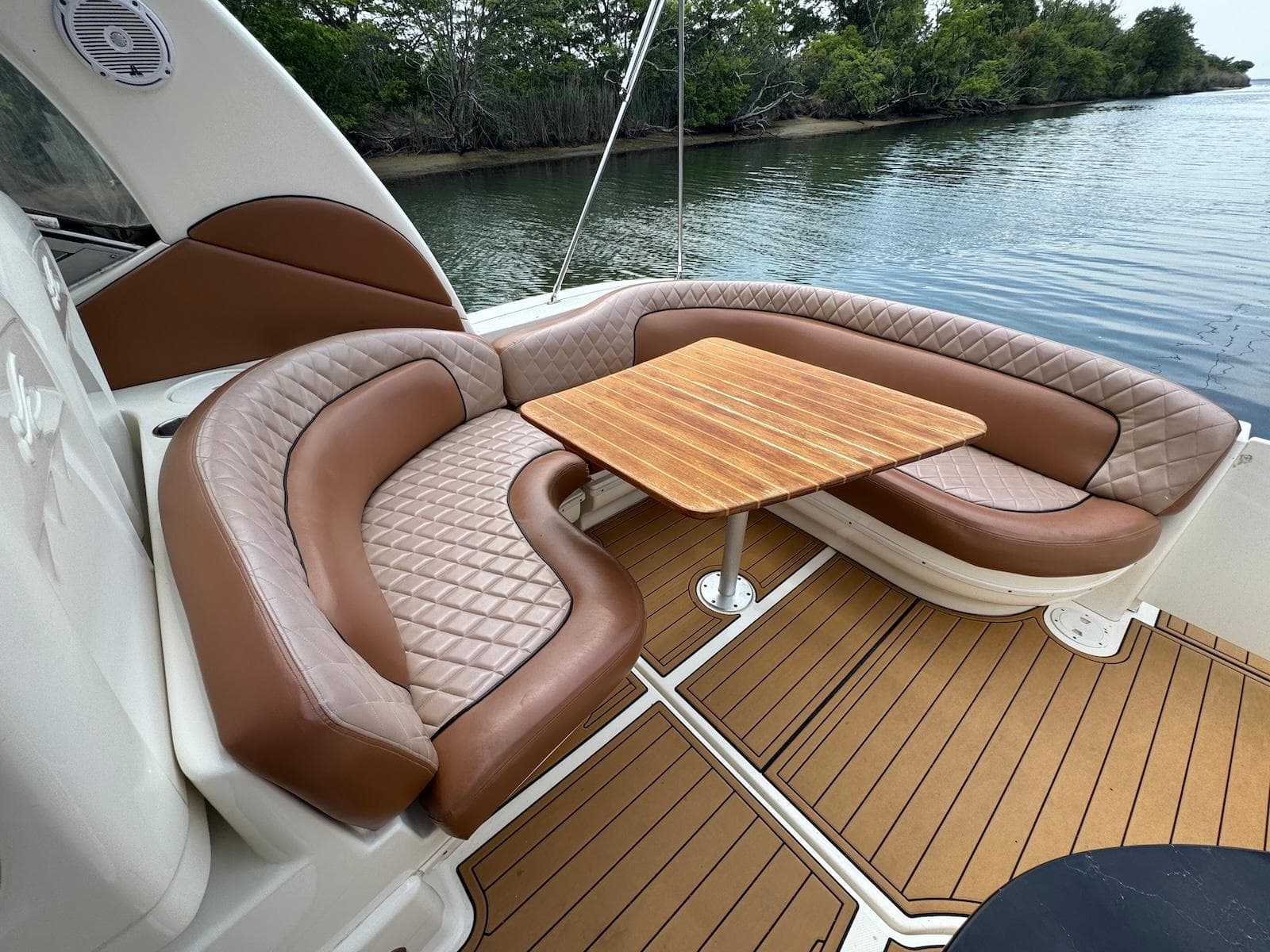 Luxurious seating area on 2003 Sea Ray 340 Sundancer yacht with wooden table and water view.