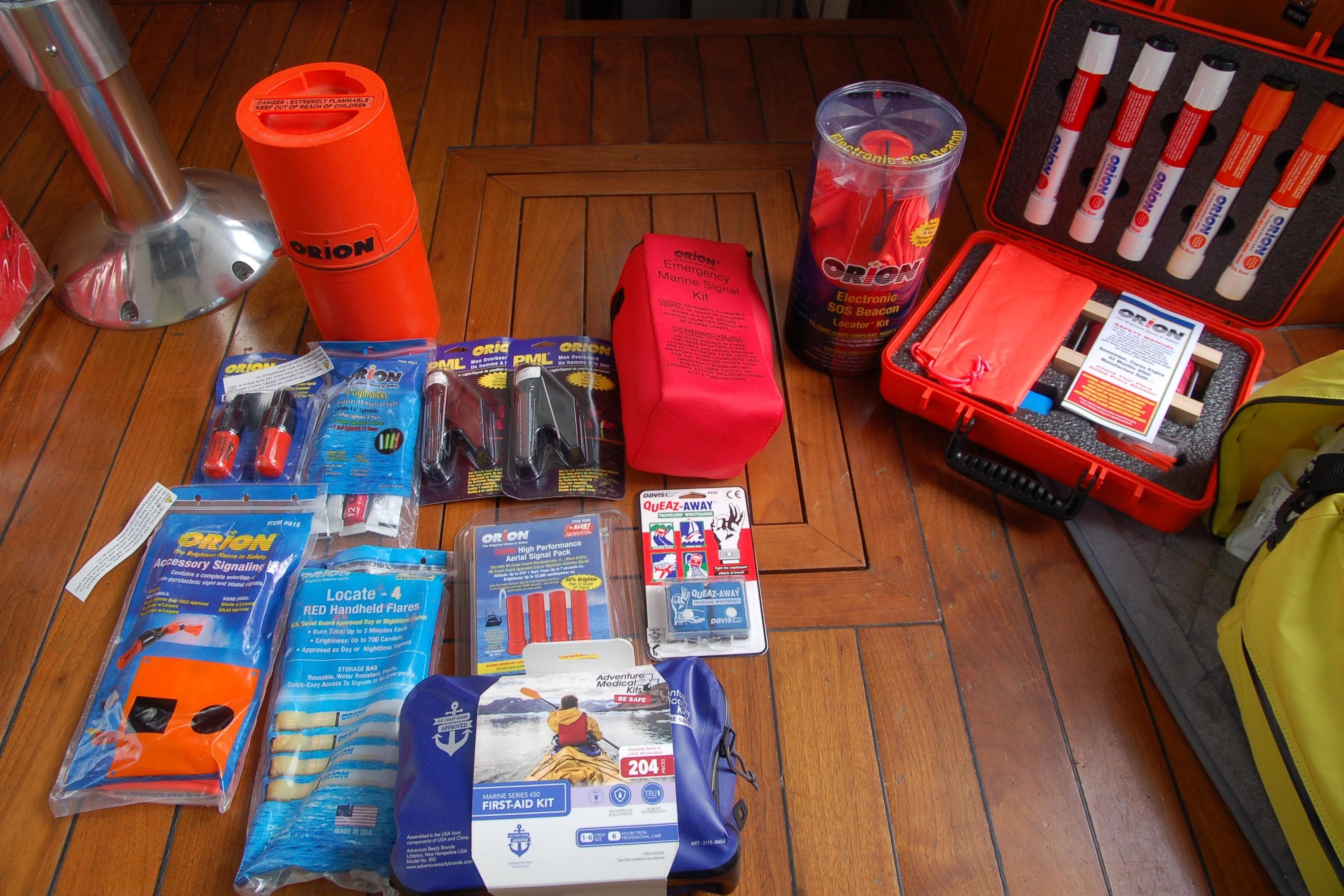 Safety equipment and emergency kits on wooden surface, including flares and first aid supplies.
