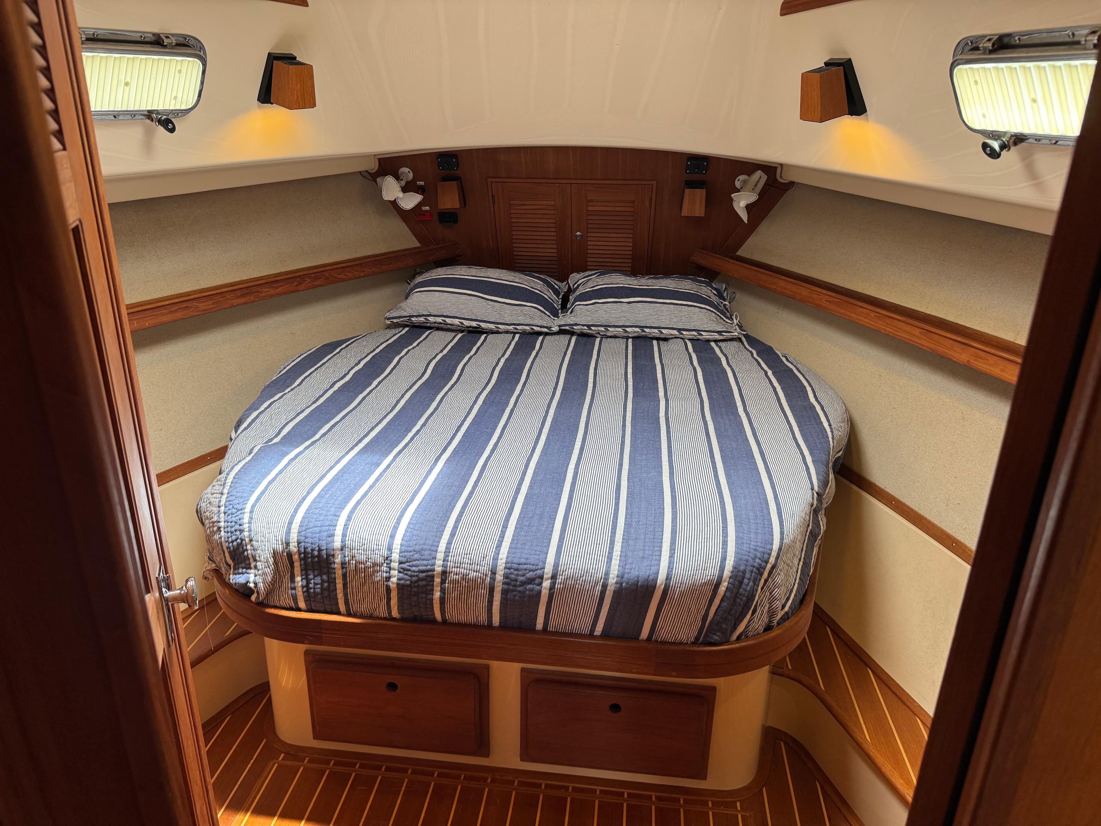 Island Packet 380 yacht cabin interior with striped bedding, wood accents, and soft lighting, 2002 model.