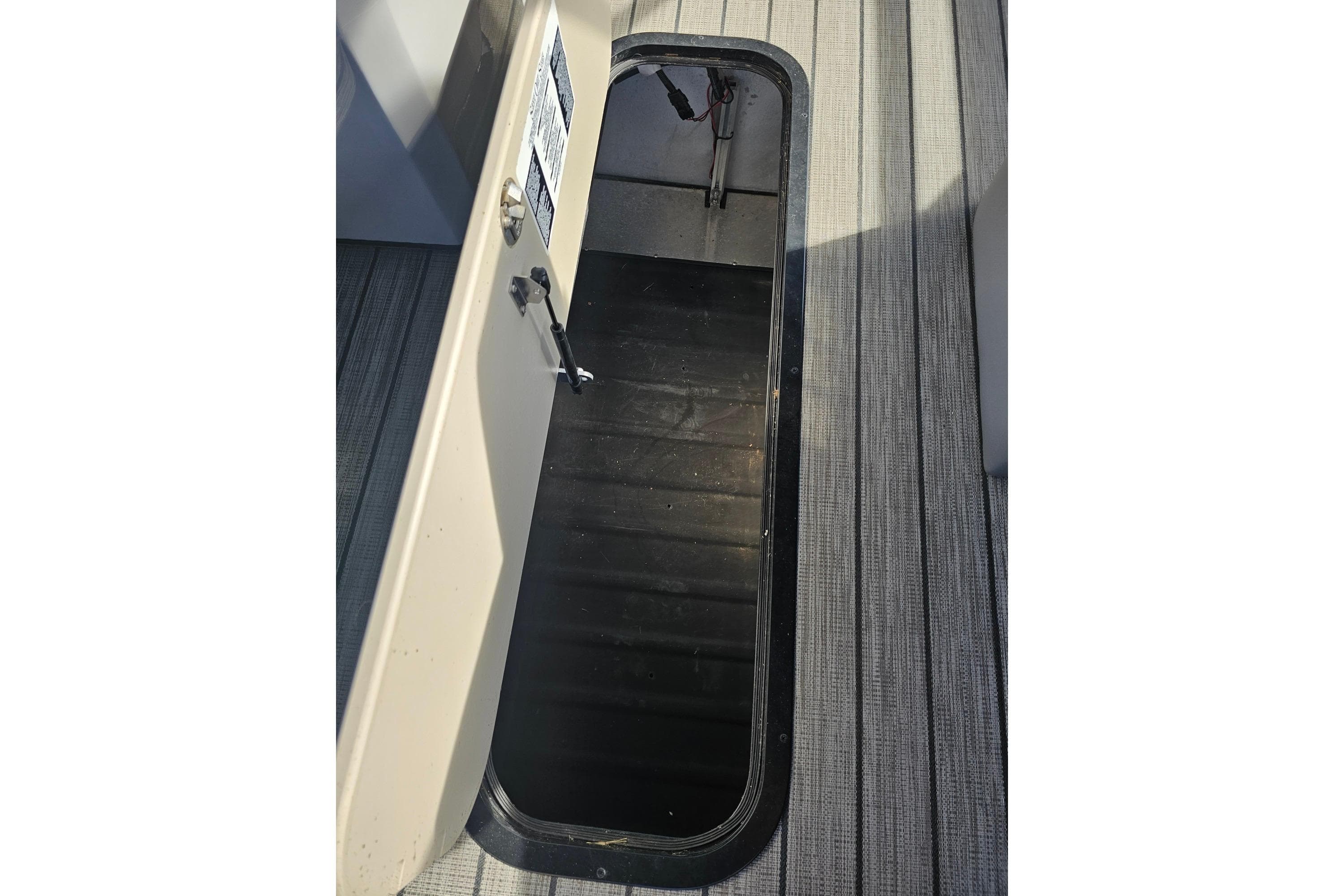 Open storage compartment on a 2024 Harris boat, featuring a sleek black interior.