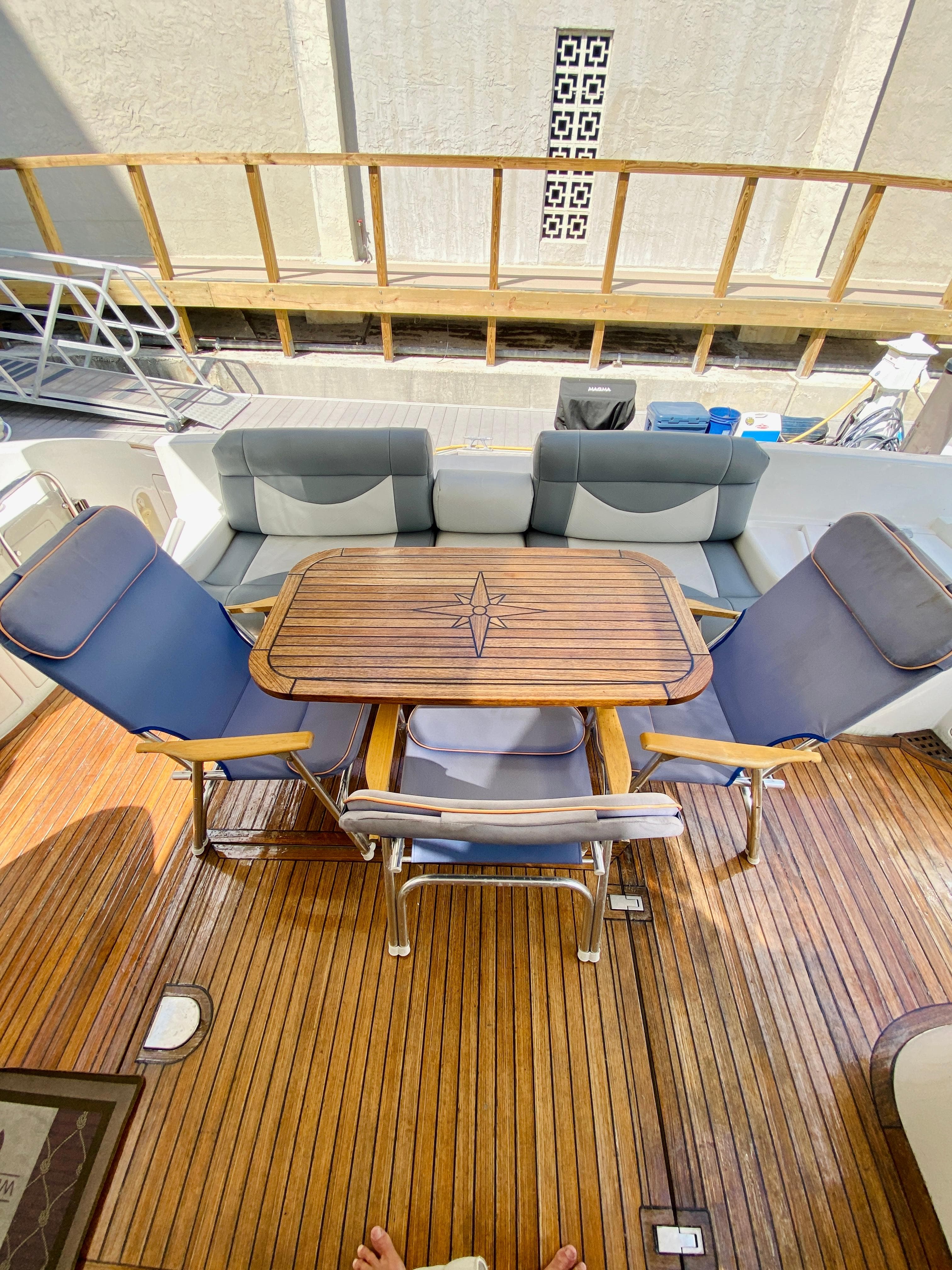 Luxury Azimut 55 yacht deck with wooden table and cushioned seating, 2002 model.