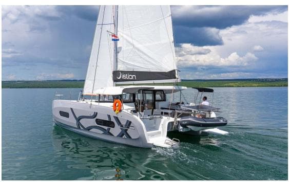 Sailing catamaran Excess 11, 2023 model, cruising on calm waters under a cloudy sky.