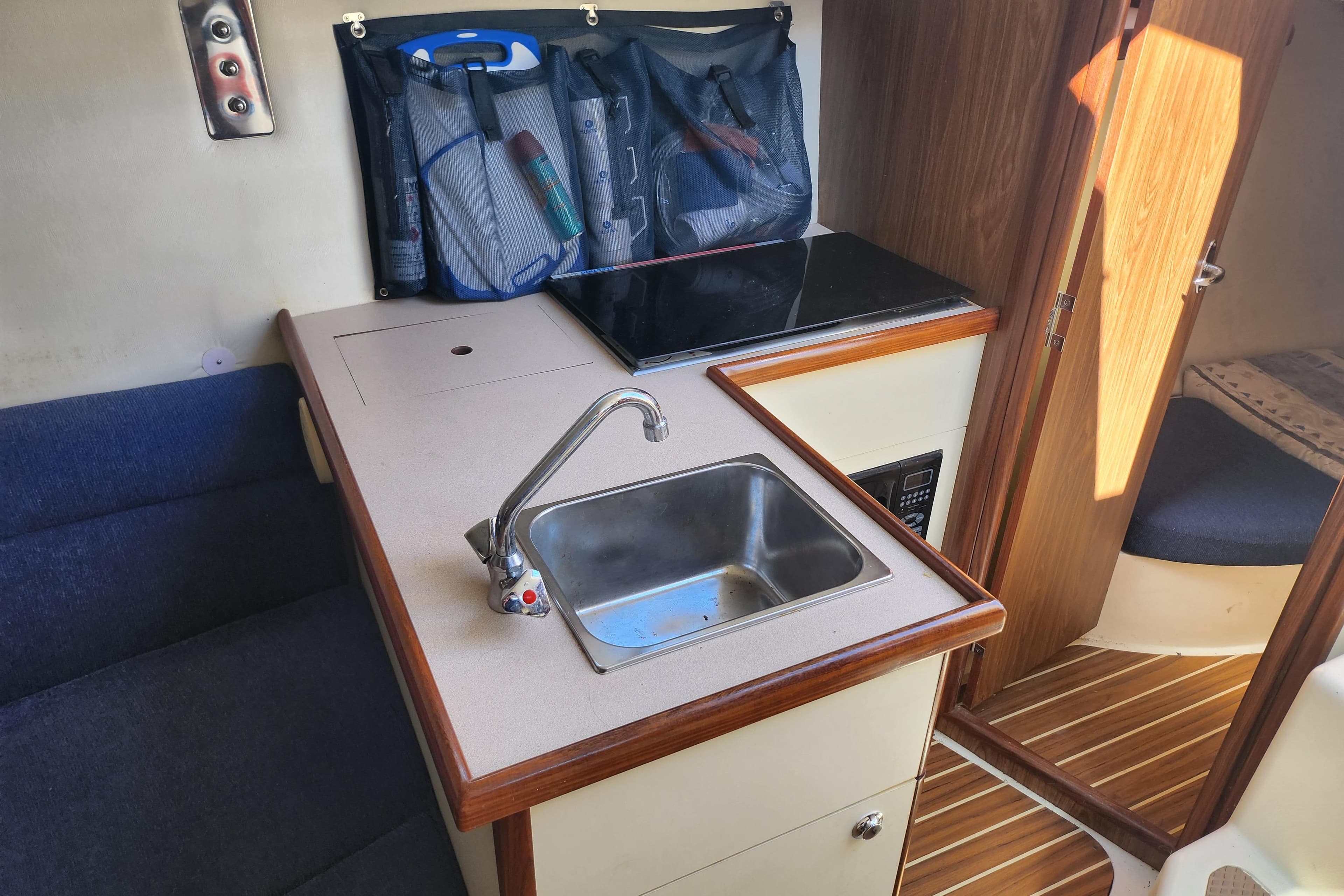 Compact kitchen area in a 2005 Hunter 27 sailboat with sink and storage.
