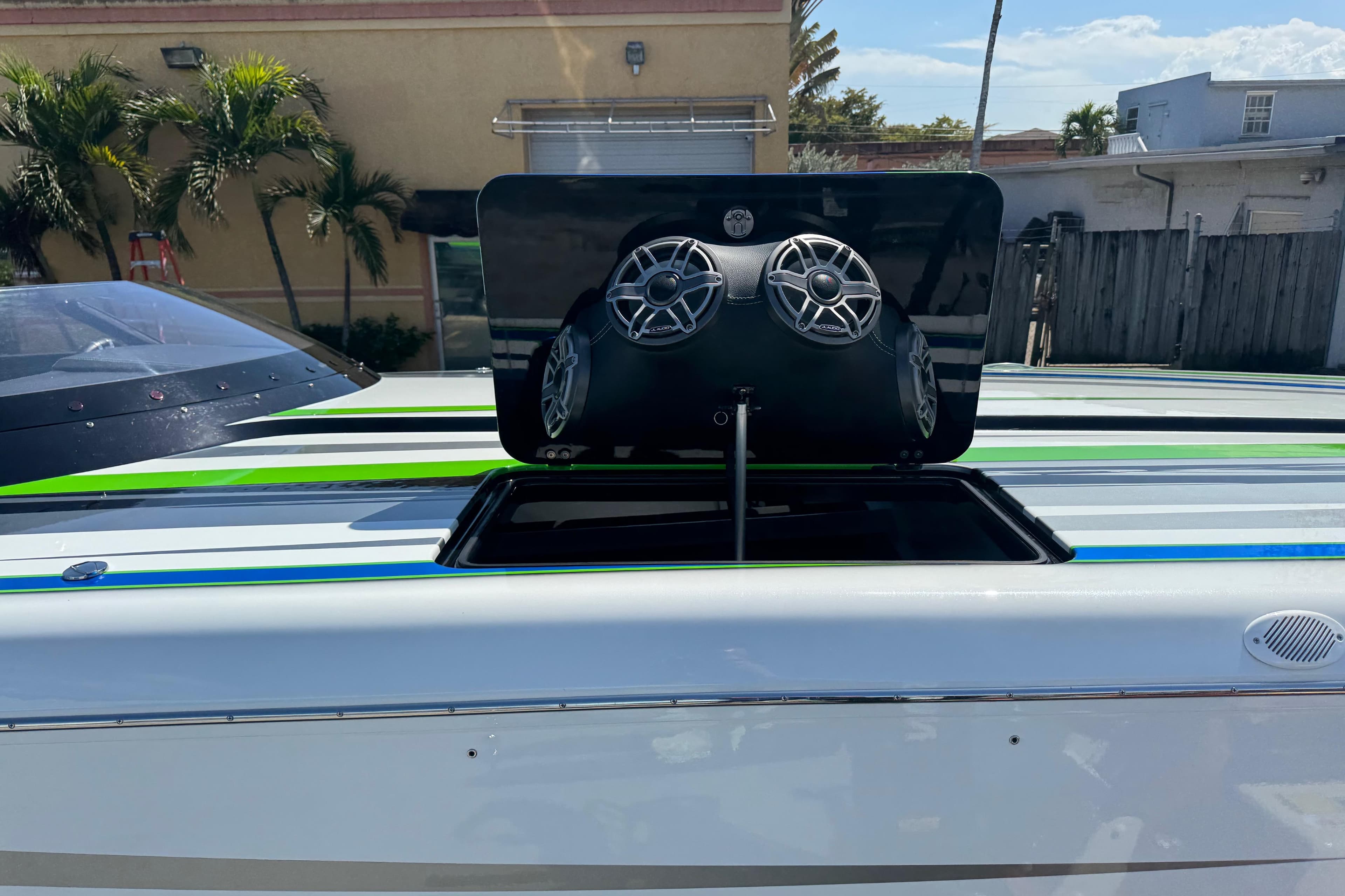 2022 MTI 390X boat with open hatch revealing speakers, set against a sunny backdrop.