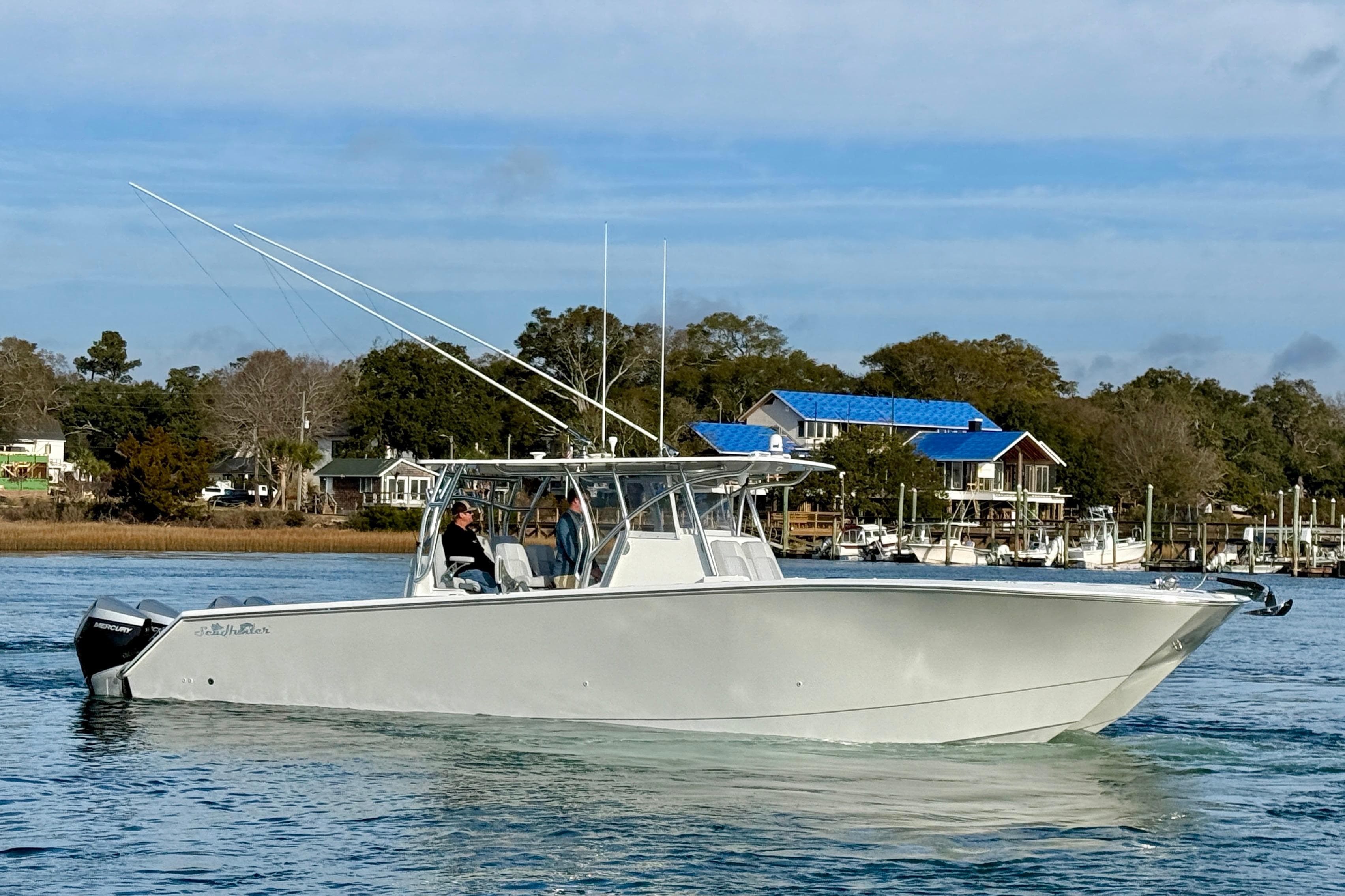 2021 SeaHunter 41 CTS boat cruising on a calm waterway near a coastal town.