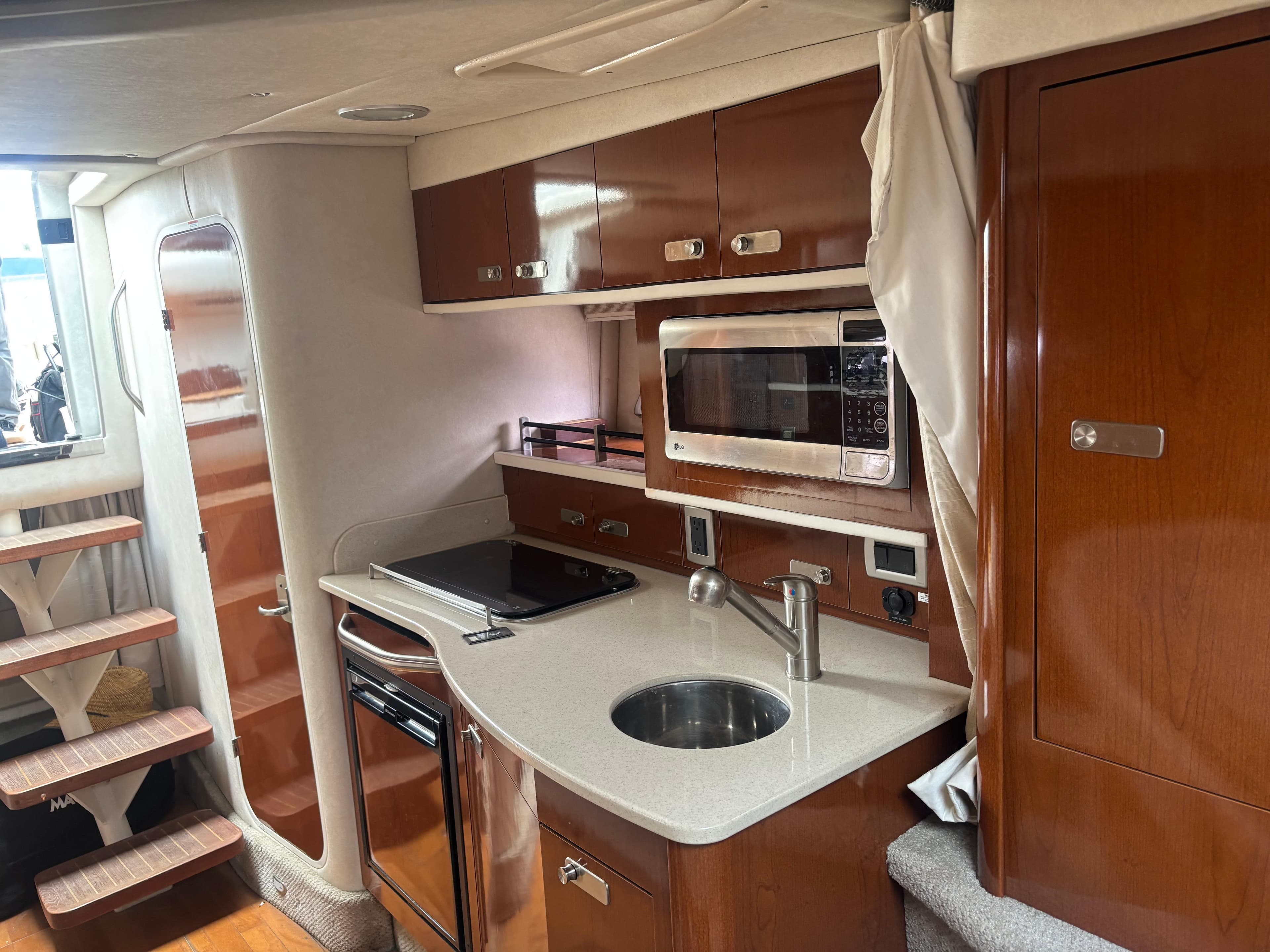 2011 Sea Ray 330 Sundancer interior kitchen with modern appliances and wooden cabinetry.
