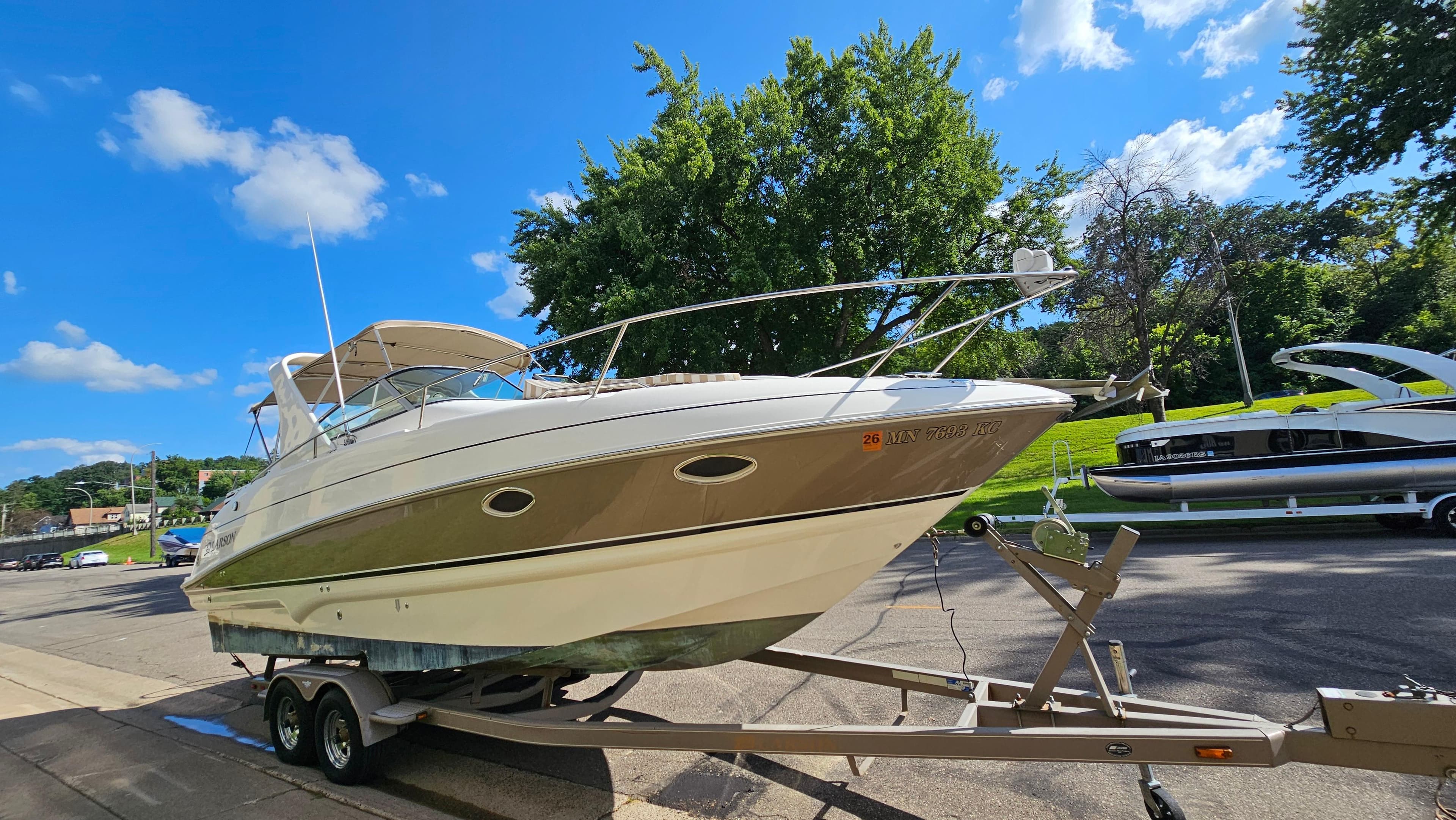 2006 Larson 274 Cabrio boat on trailer, parked outdoors under a clear blue sky.