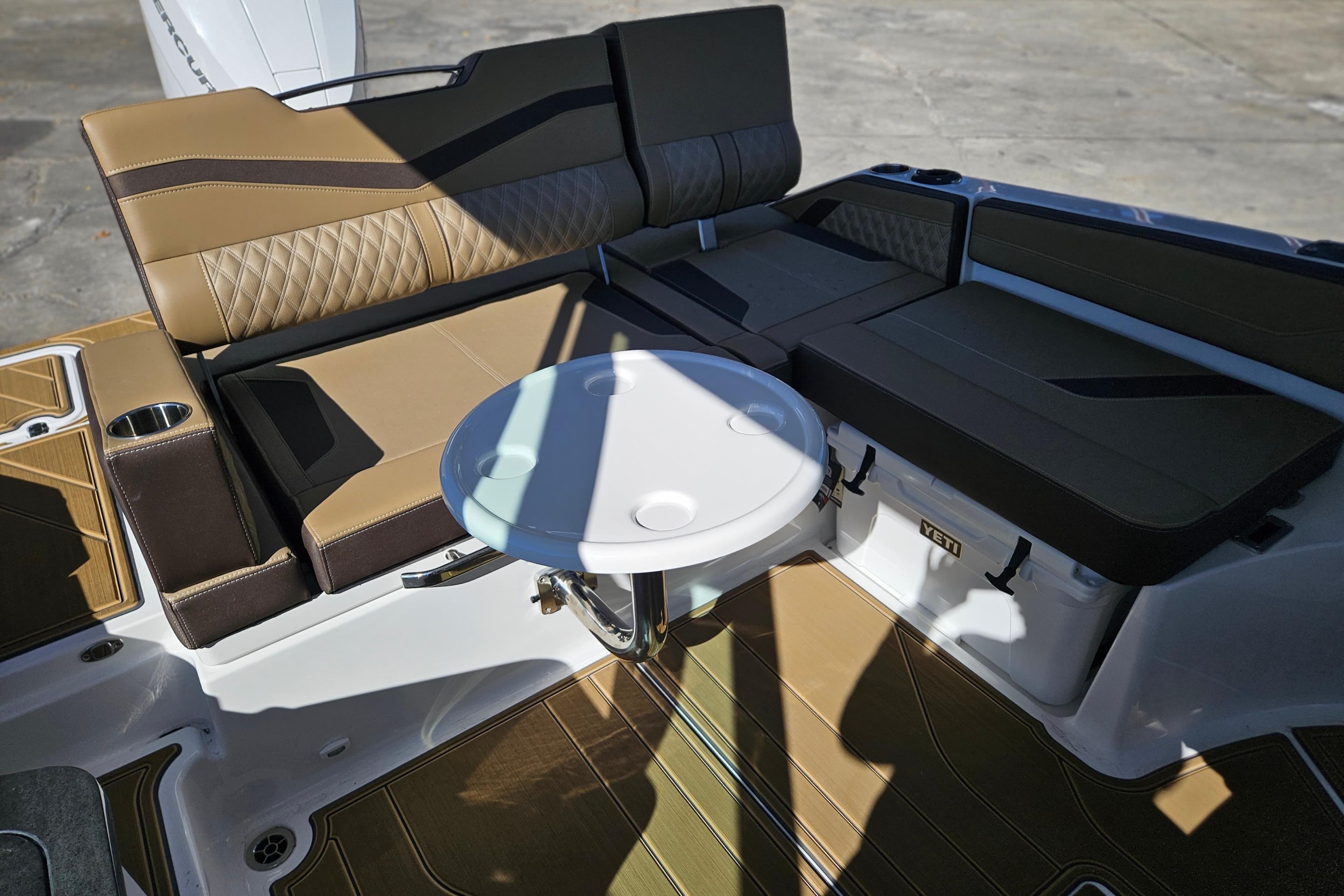 Luxurious seating area on 2026 Monterey Elite 27 OB boat with table and storage.