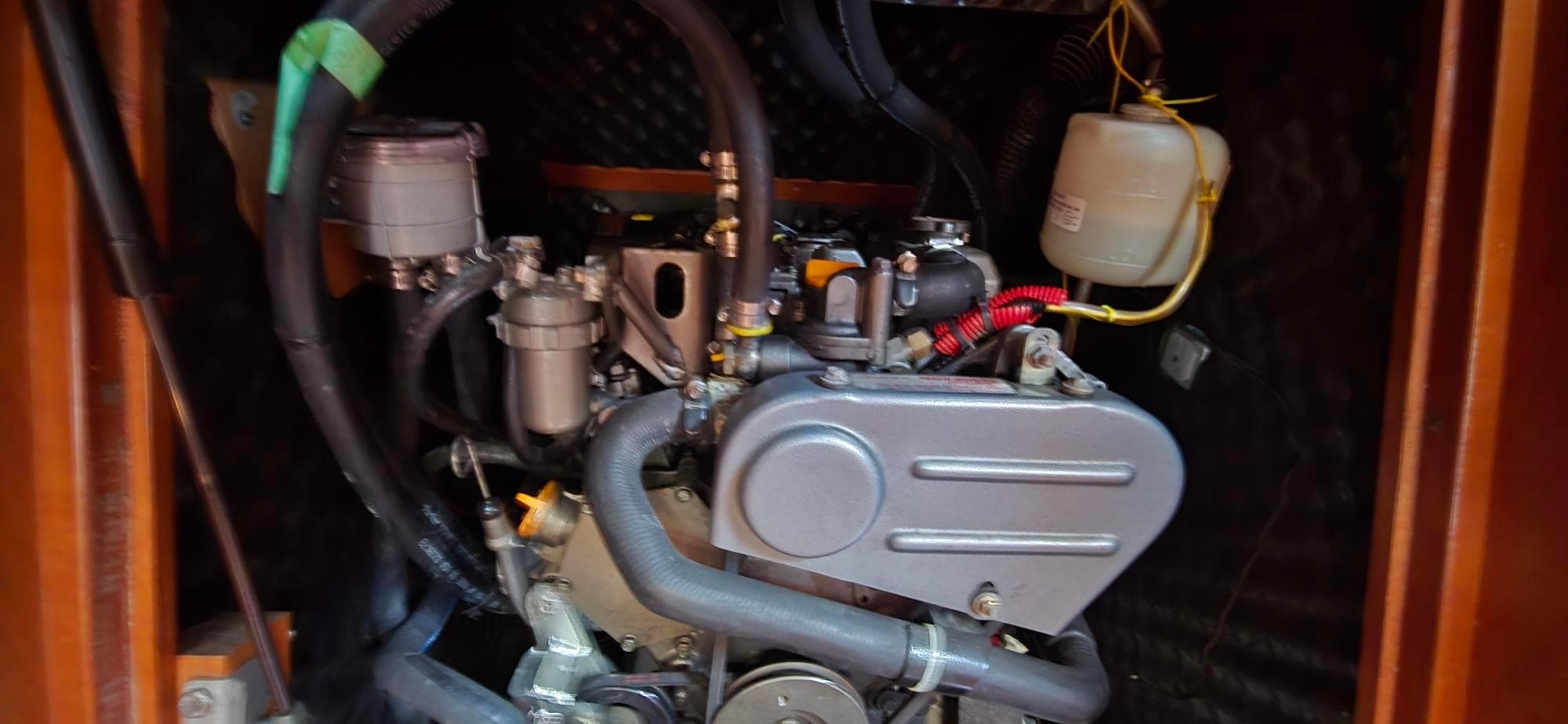 Engine compartment of a 2008 Beneteau 343 sailboat, showcasing mechanical components and hoses.