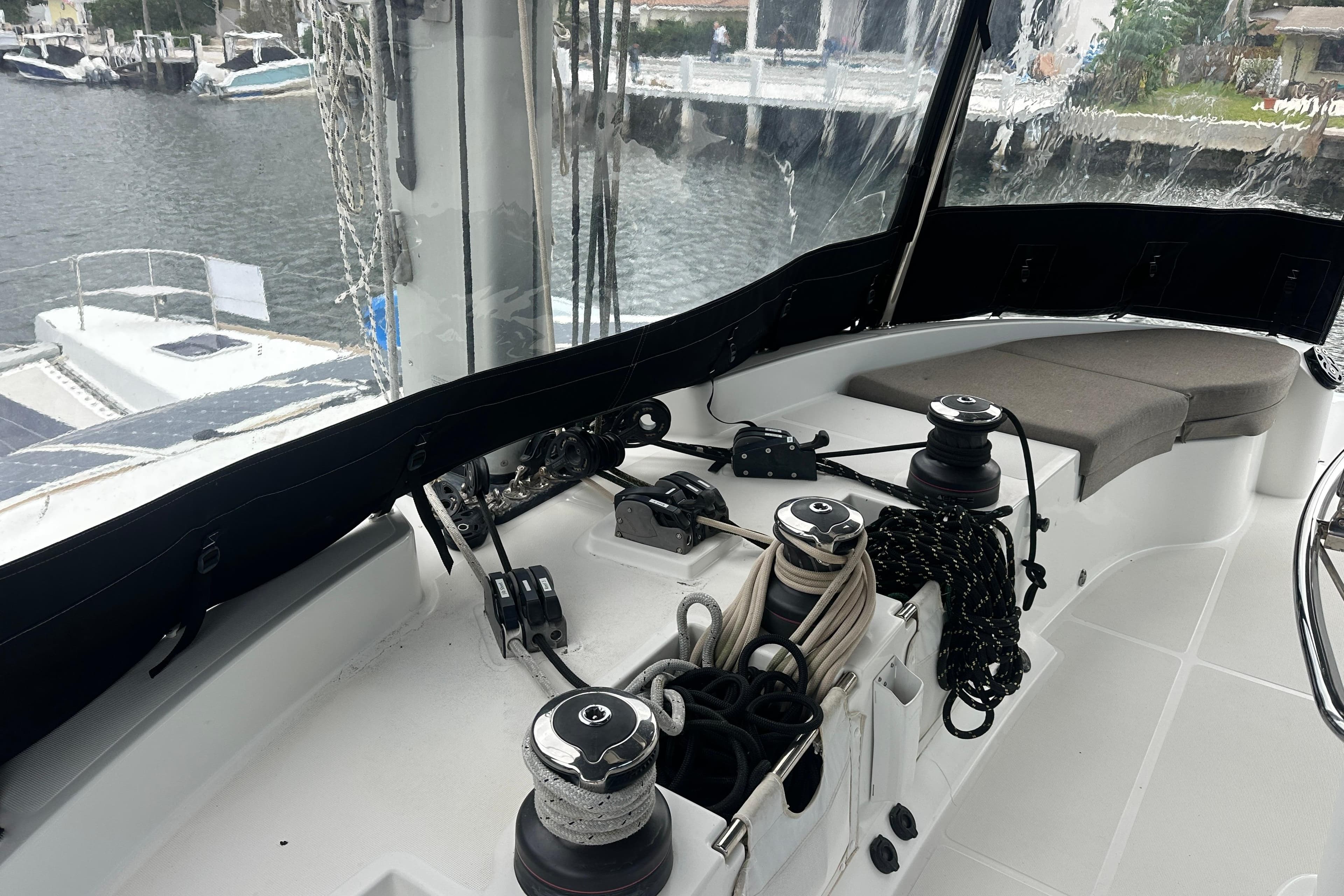Cockpit of 2017 Lagoon 52 F yacht with winches and ropes, docked by the water.