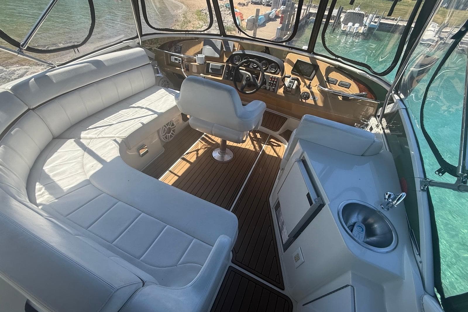 2004 Carver 396 Motor Yacht interior with helm, seating, and sink, docked by clear water.