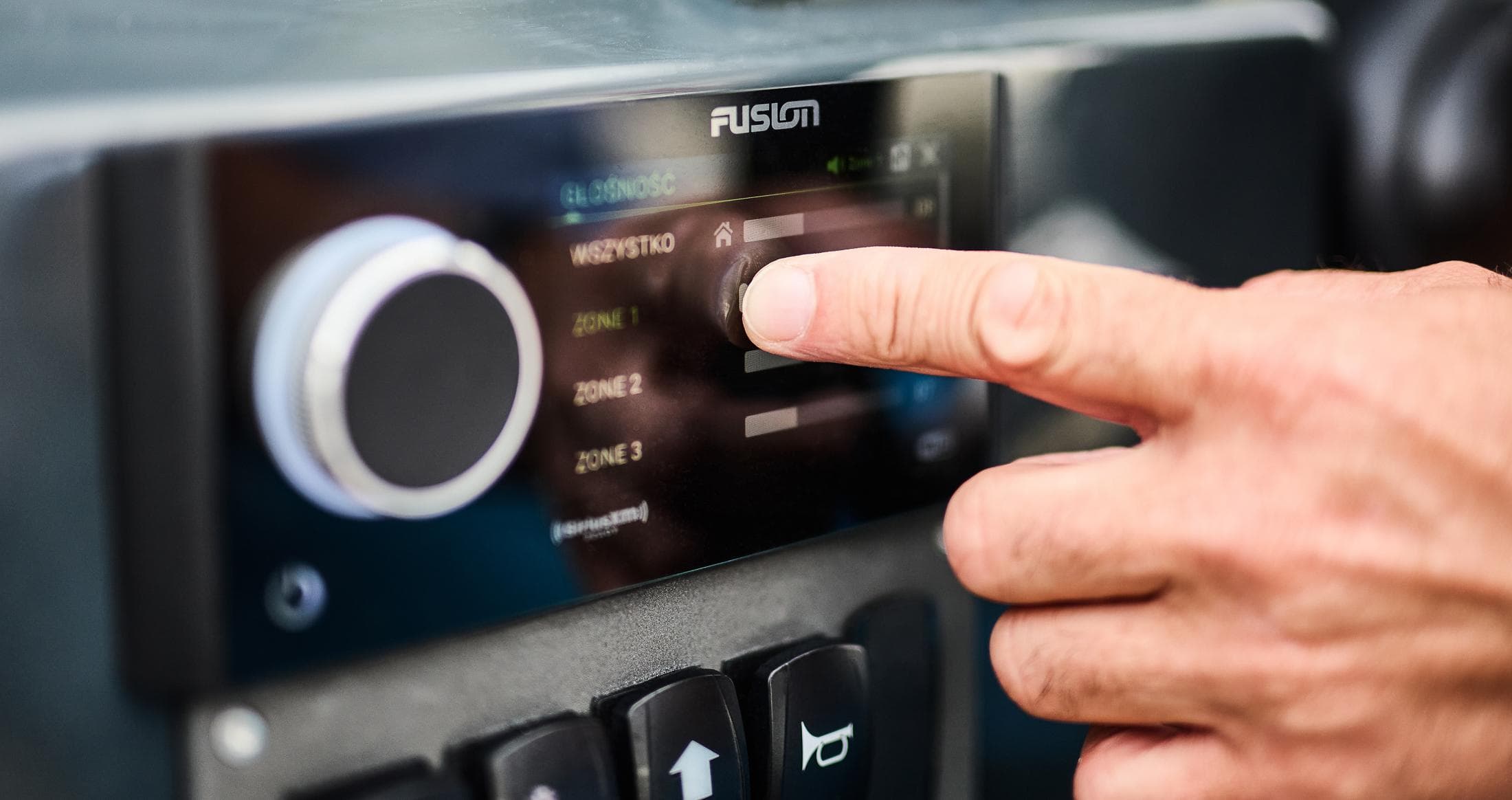 Close-up of a hand adjusting a Fusion audio system in a 2025 Skamander Sorrento.