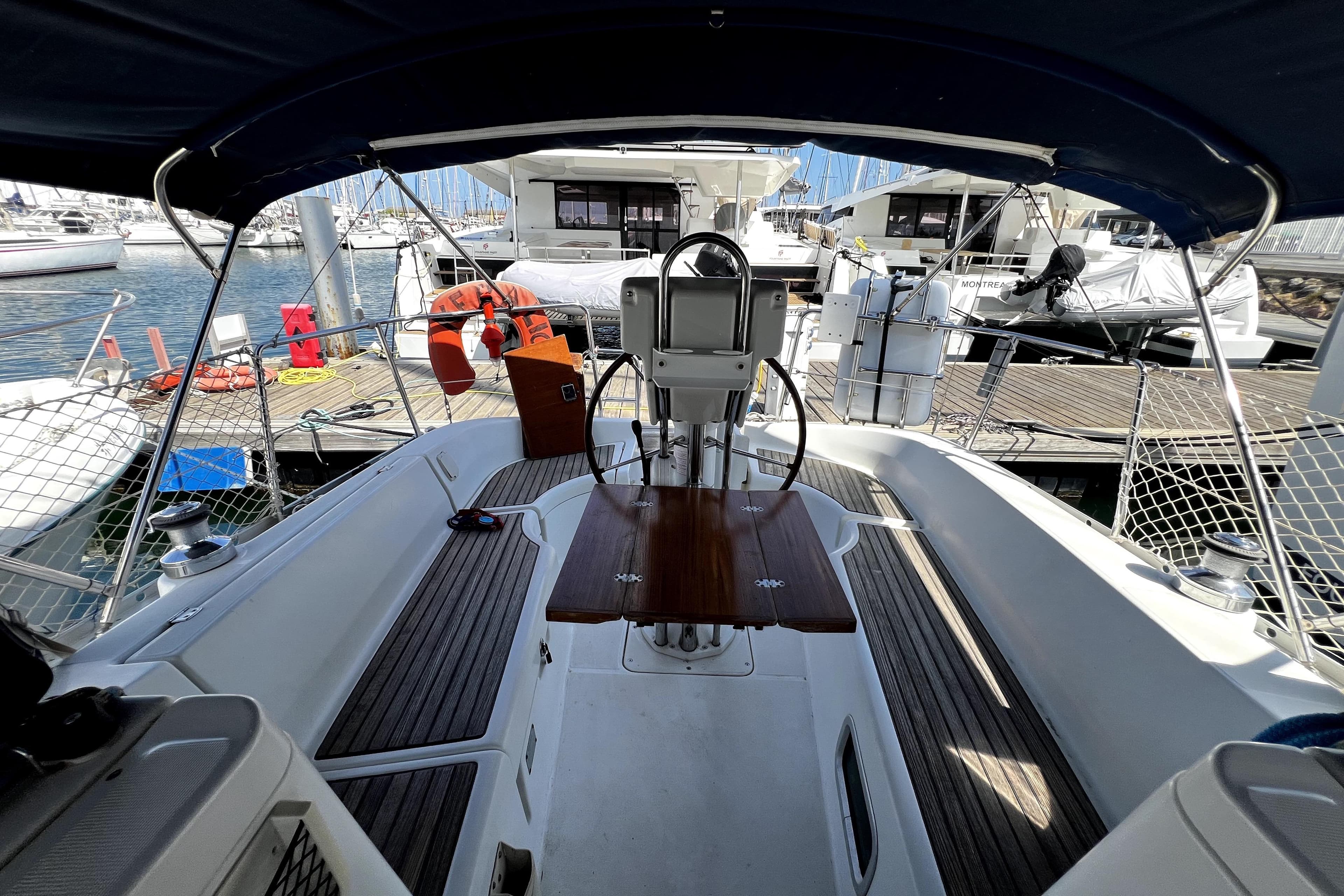2004 Beneteau Oceanis Clipper 323 yacht cockpit with wooden table, docked at marina.