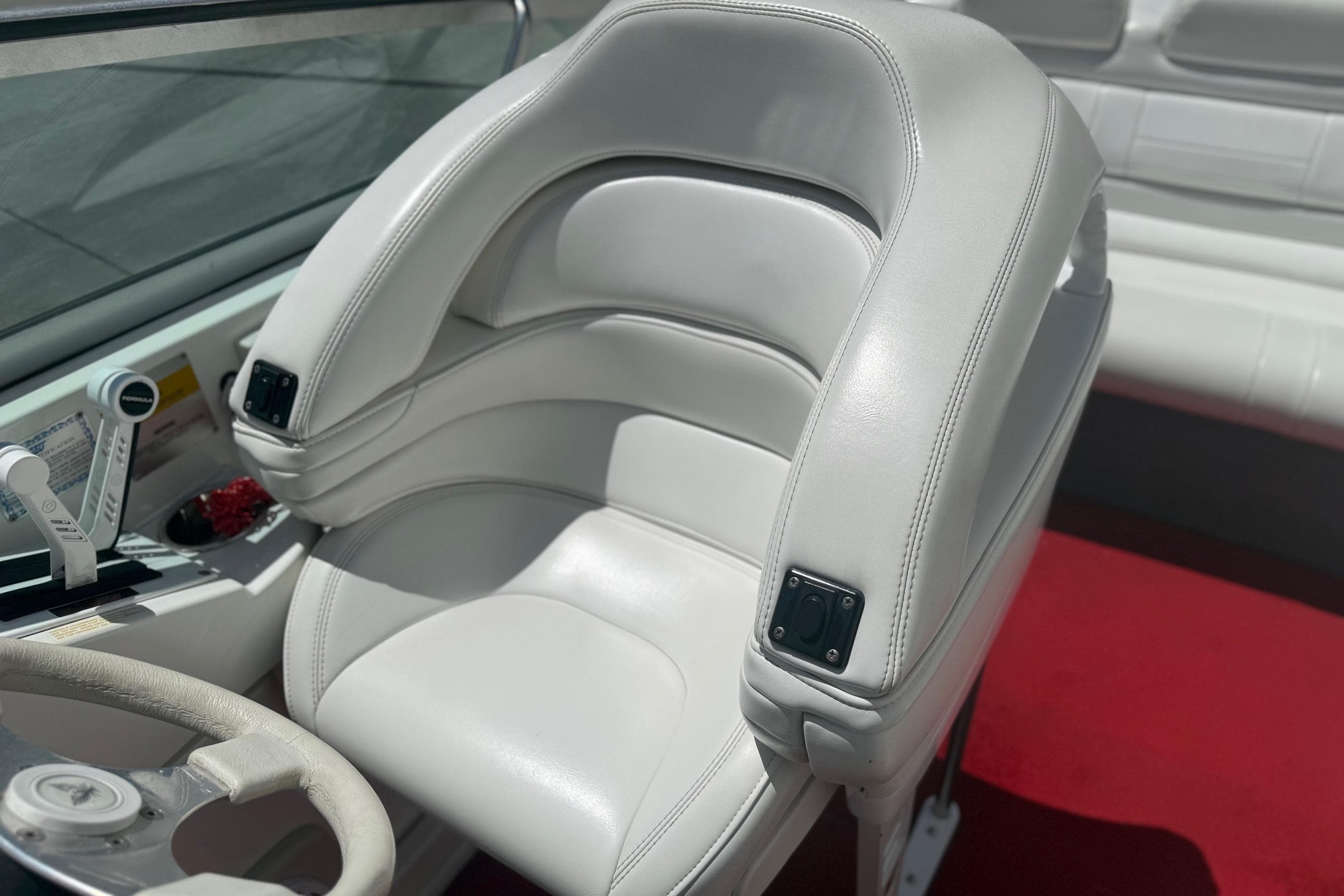 2001 Formula 353 FASTech boat interior with white leather seating and red carpet.