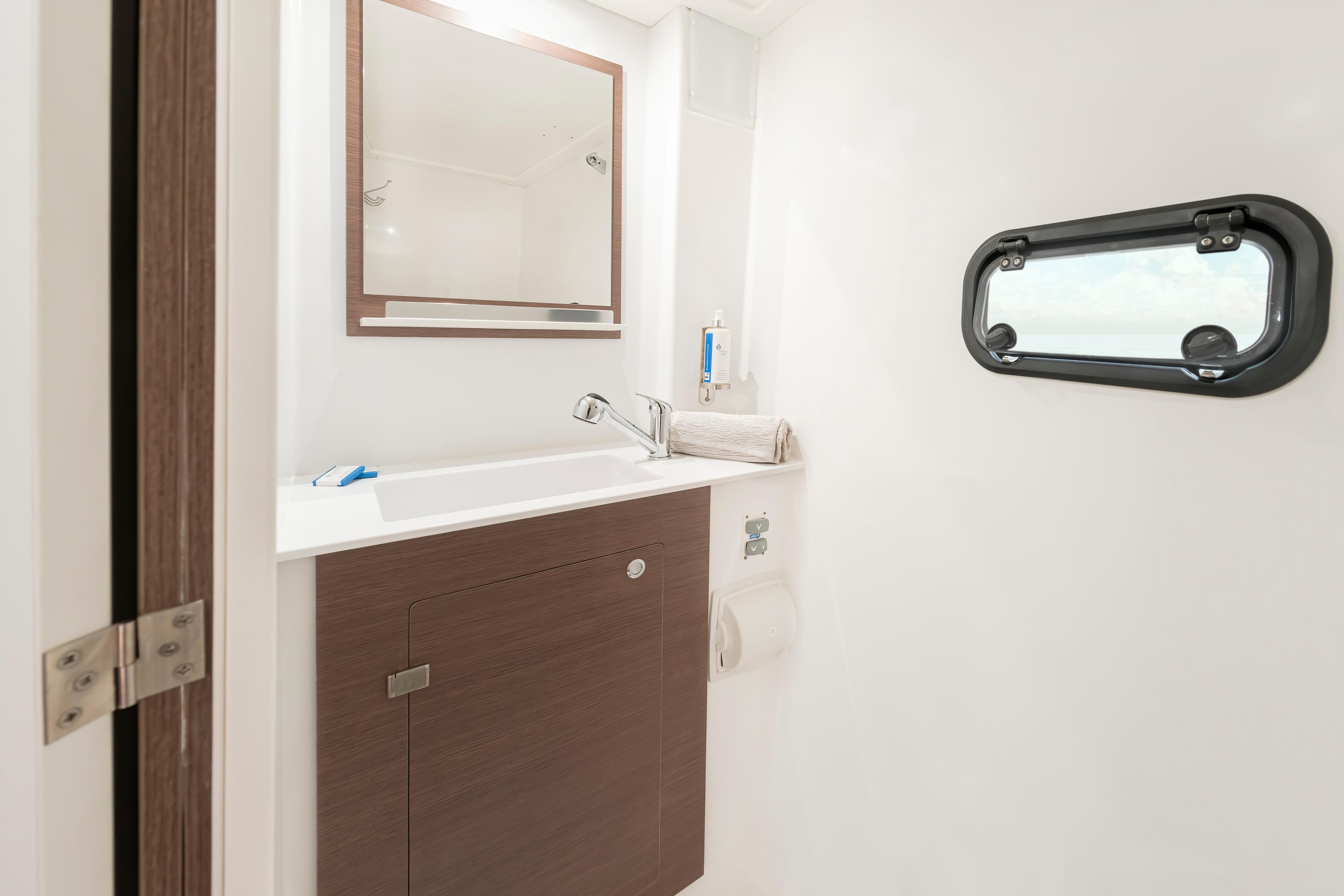 Modern bathroom interior of 2025 Bali CATSPACE SAIL yacht with sleek design and porthole window.