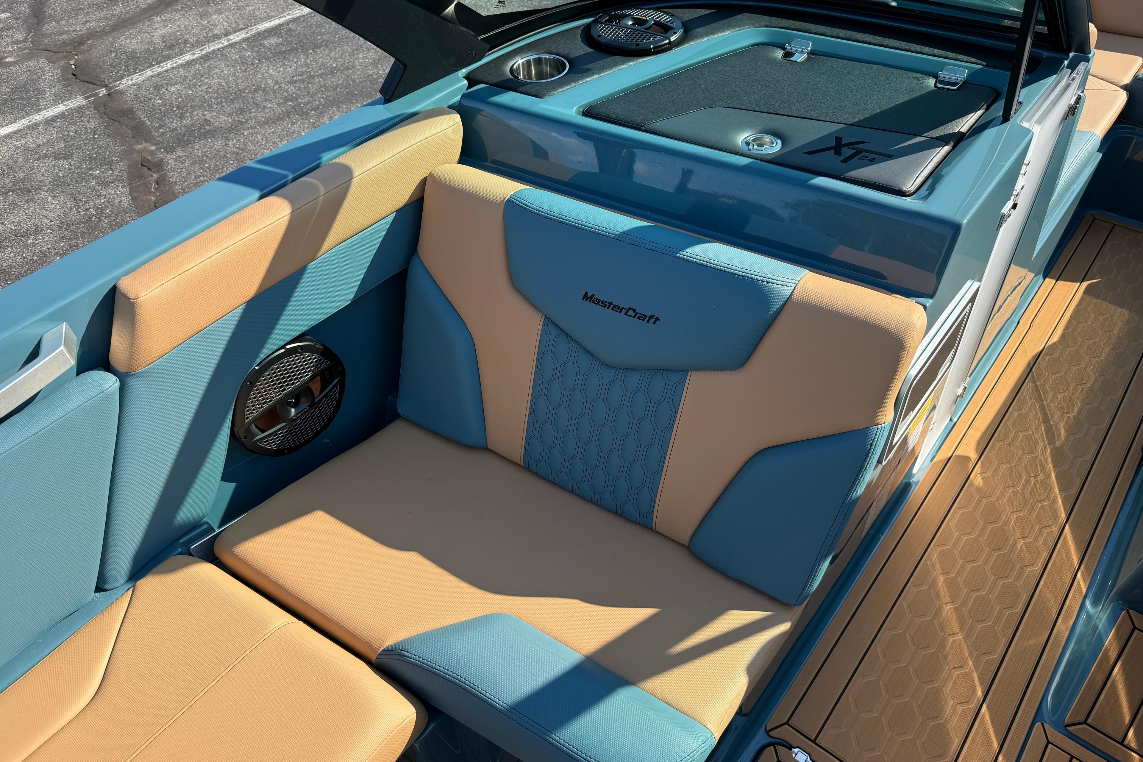 2025 MasterCraft XT24 boat interior with blue and tan seating, speaker, and storage compartment.