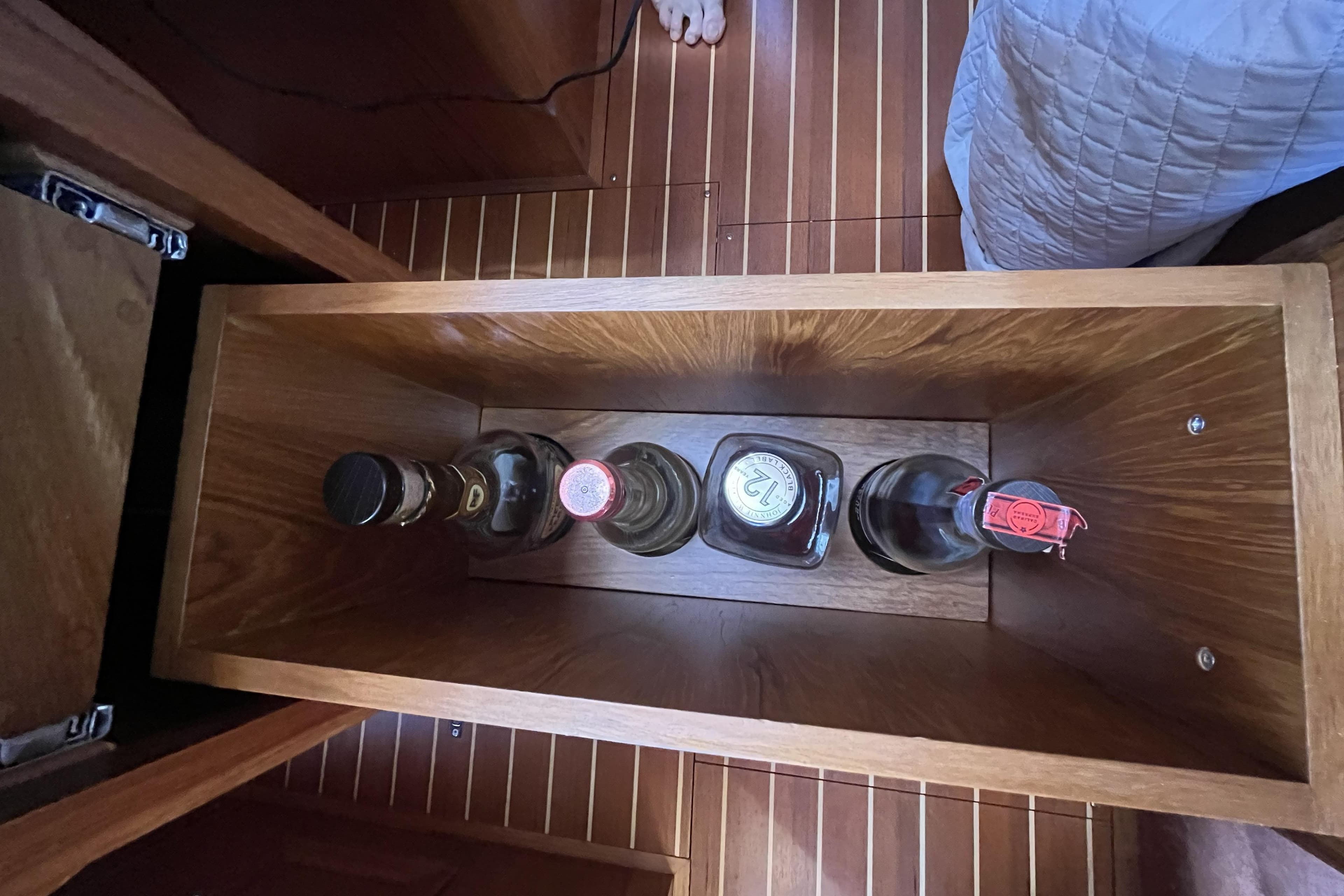 Wooden storage compartment on a 2017 Rustler 37 yacht, holding four bottles.