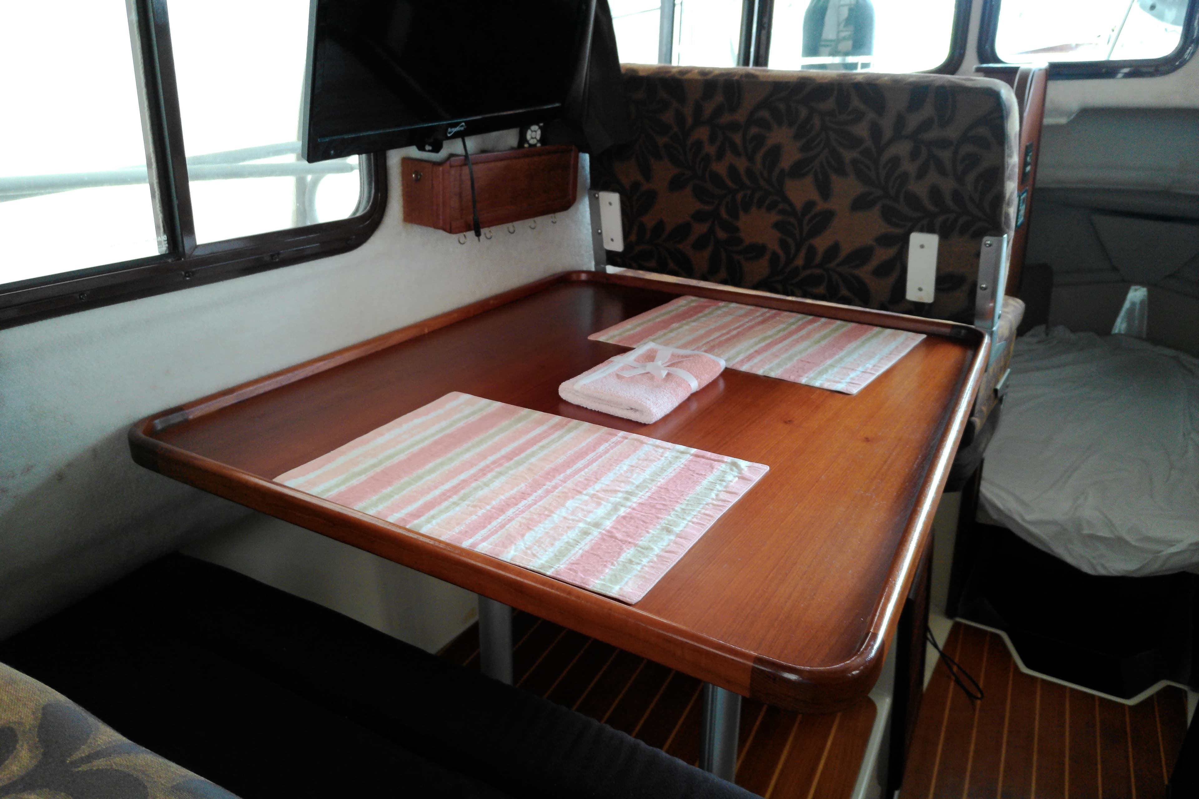 2010 Ranger Tugs R-25 interior dining area with wooden table and patterned seating.
