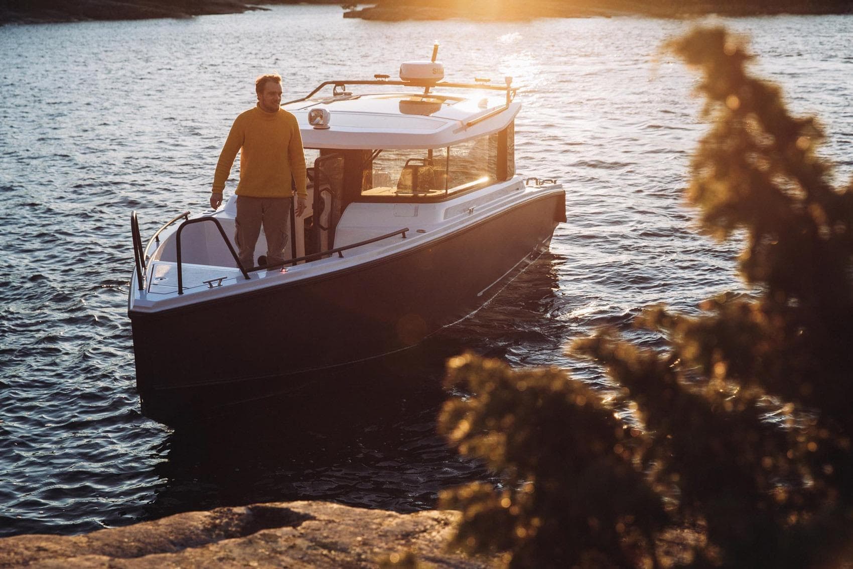 Man on XO EXPLR 9 boat at sunset, 2027 model, on calm water.