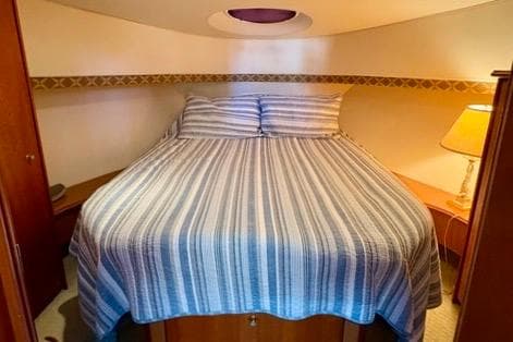 Cozy bedroom in 2008 Silverton 36 Convertible yacht with striped bedding and warm lighting.