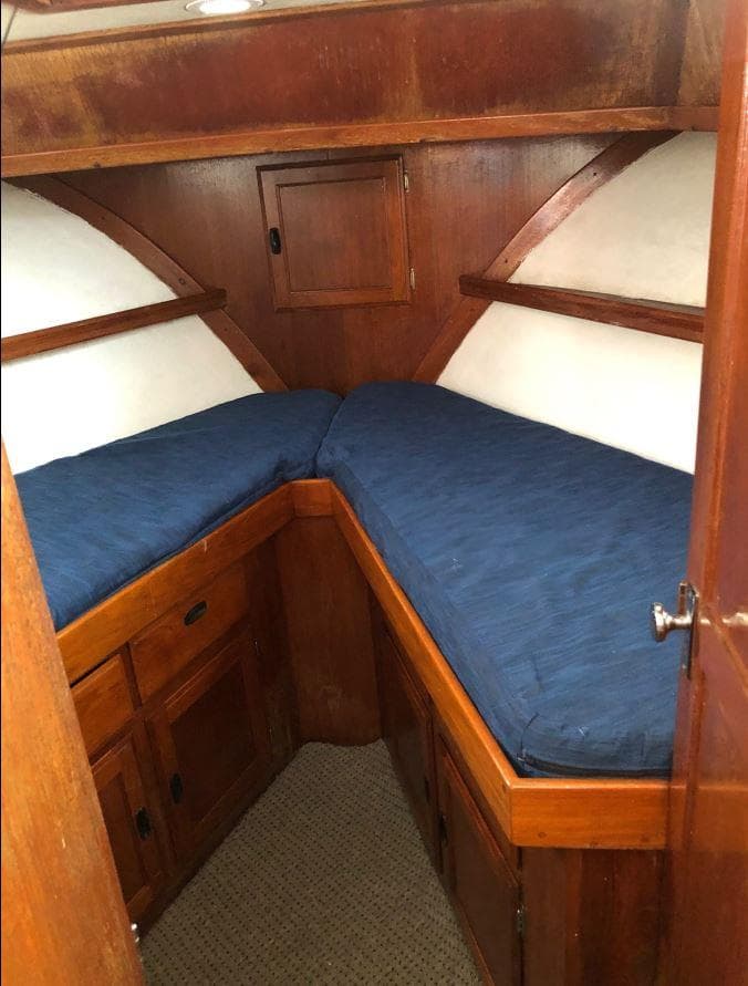 1974 DeFever 40 Passage Maker Trawler Yacht cabin with wooden interior and blue bedding.