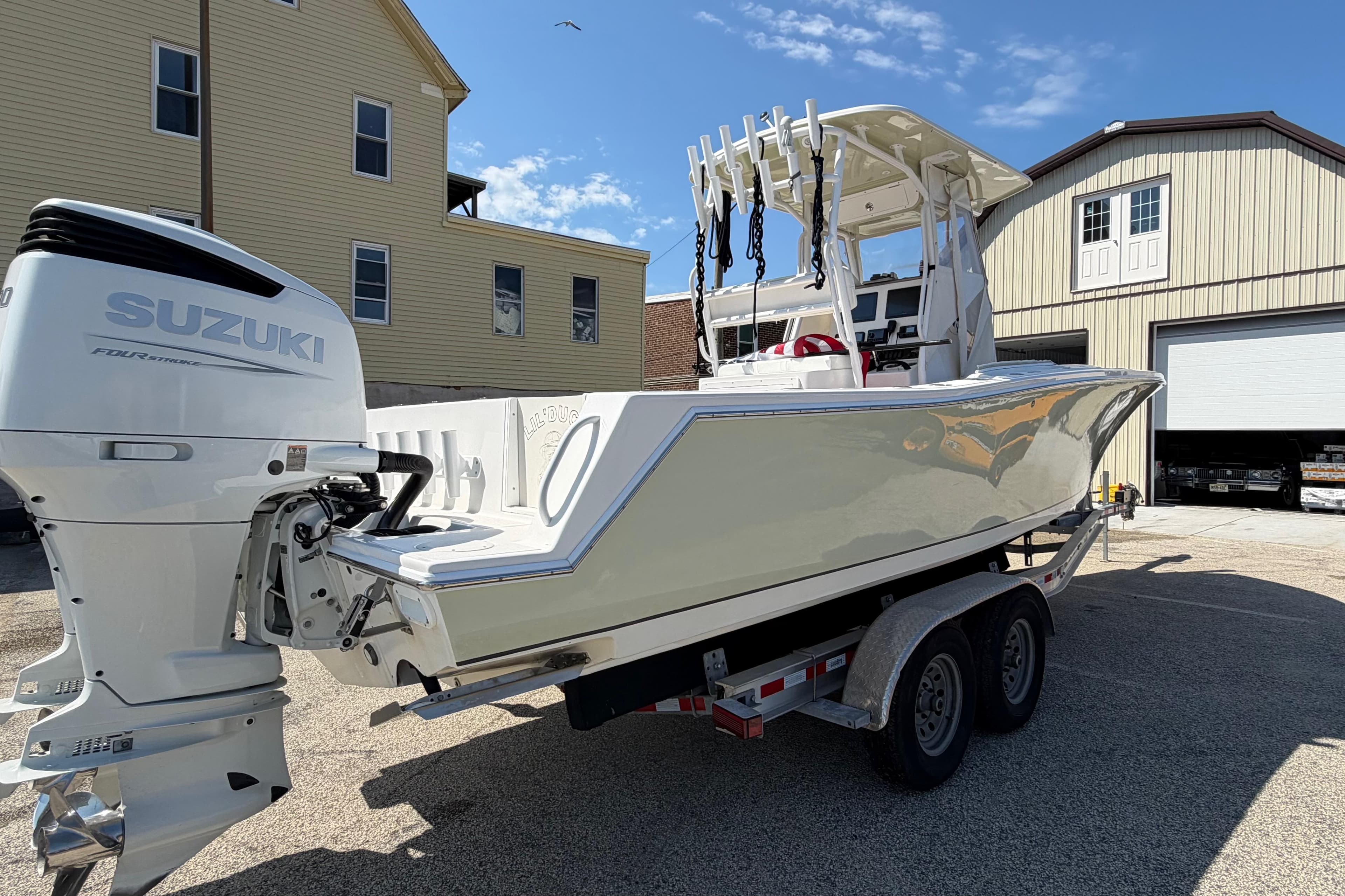 2023 Ocean Runner 2 boat with Suzuki engine on a trailer, parked near buildings.