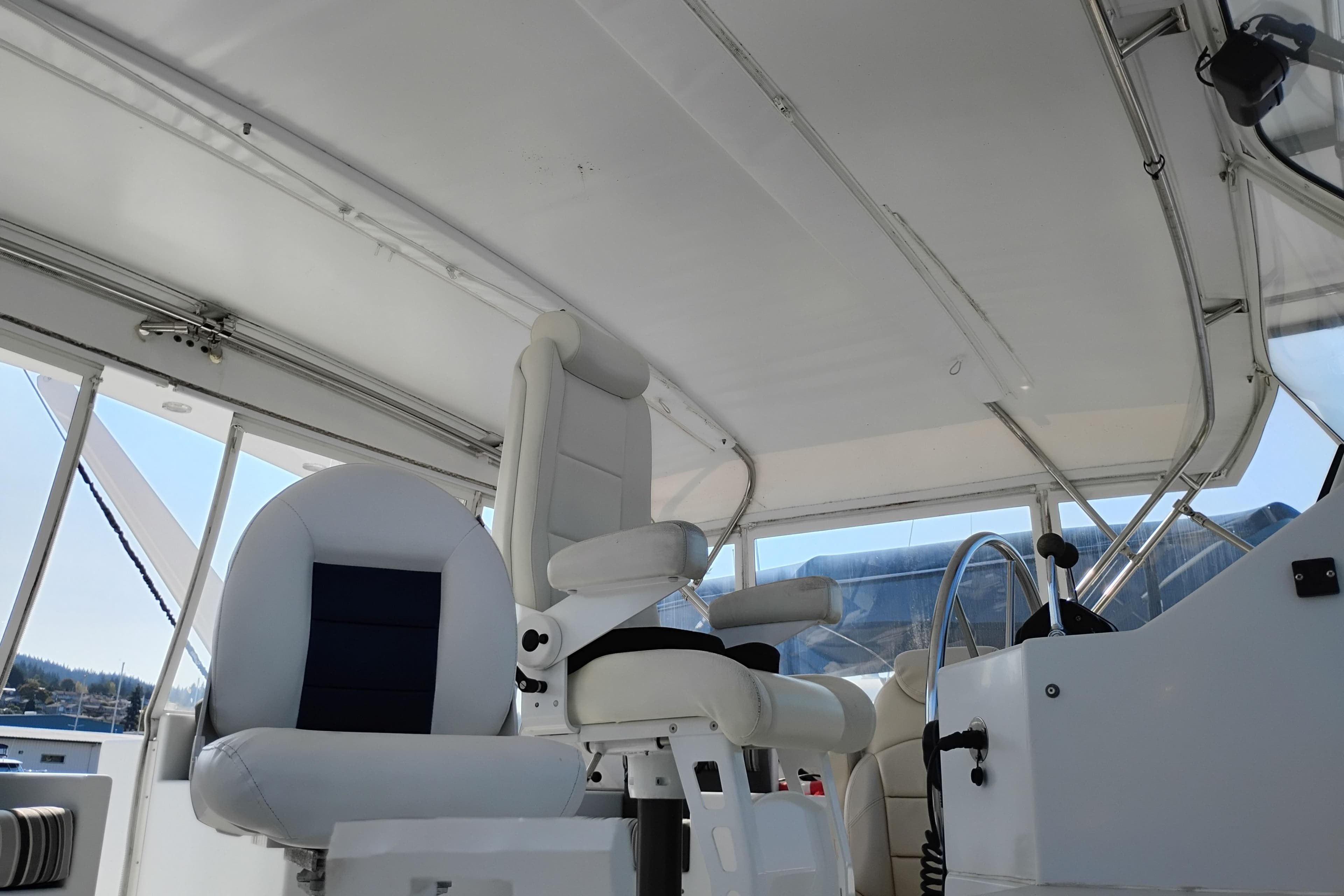 Interior view of 1995 Queenship 62 Pilothouse Motor Yacht helm with white seating.