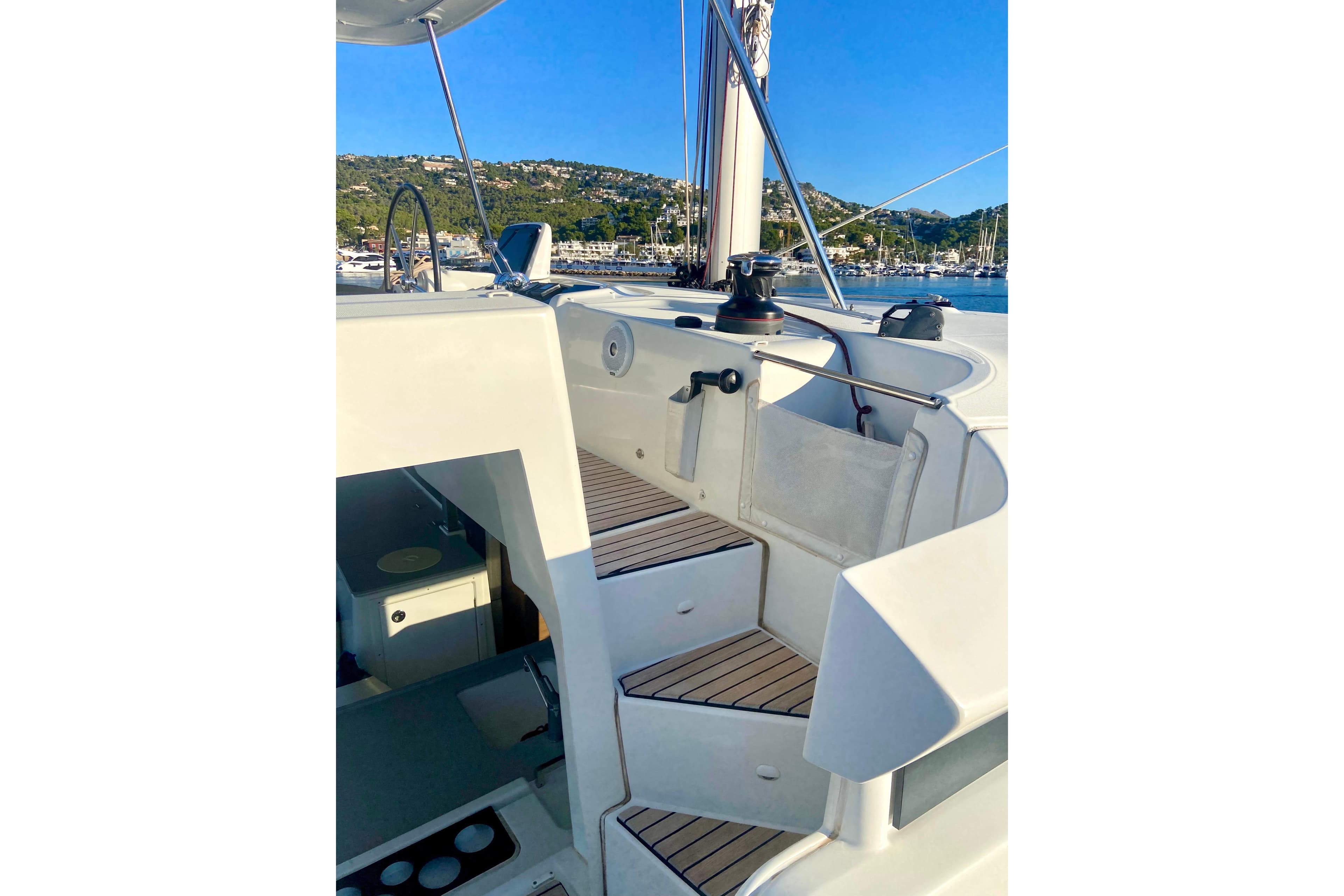 2020 Lagoon 46 yacht deck with steps, marina view, clear blue sky.
