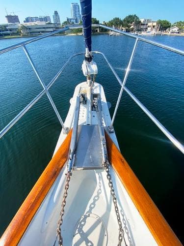 Bow view of 1989 Irwin 54 sailboat on calm water, city skyline in background.