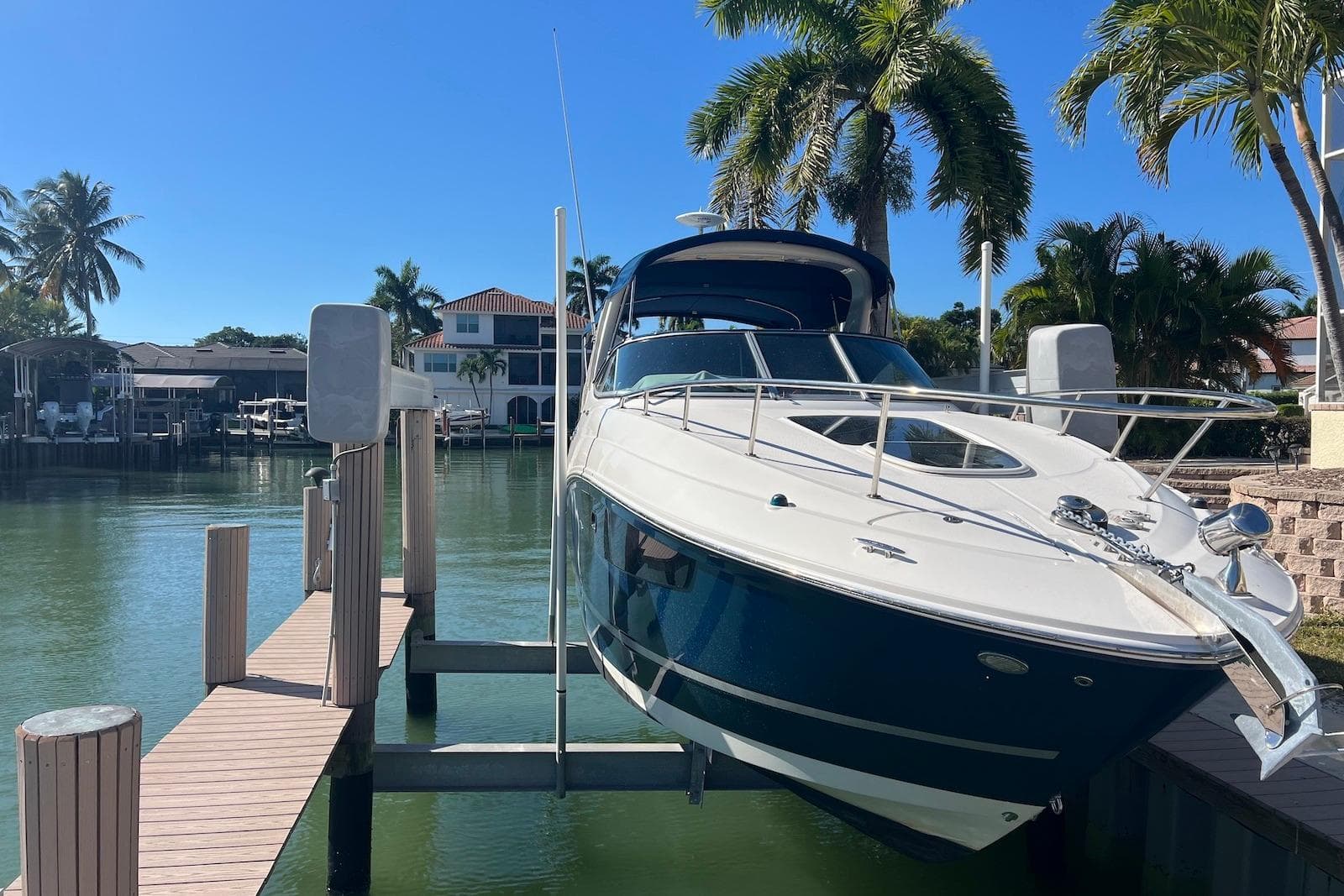 2018 Sea Ray Sundancer 280 docked, surrounded by palm trees and waterfront homes.