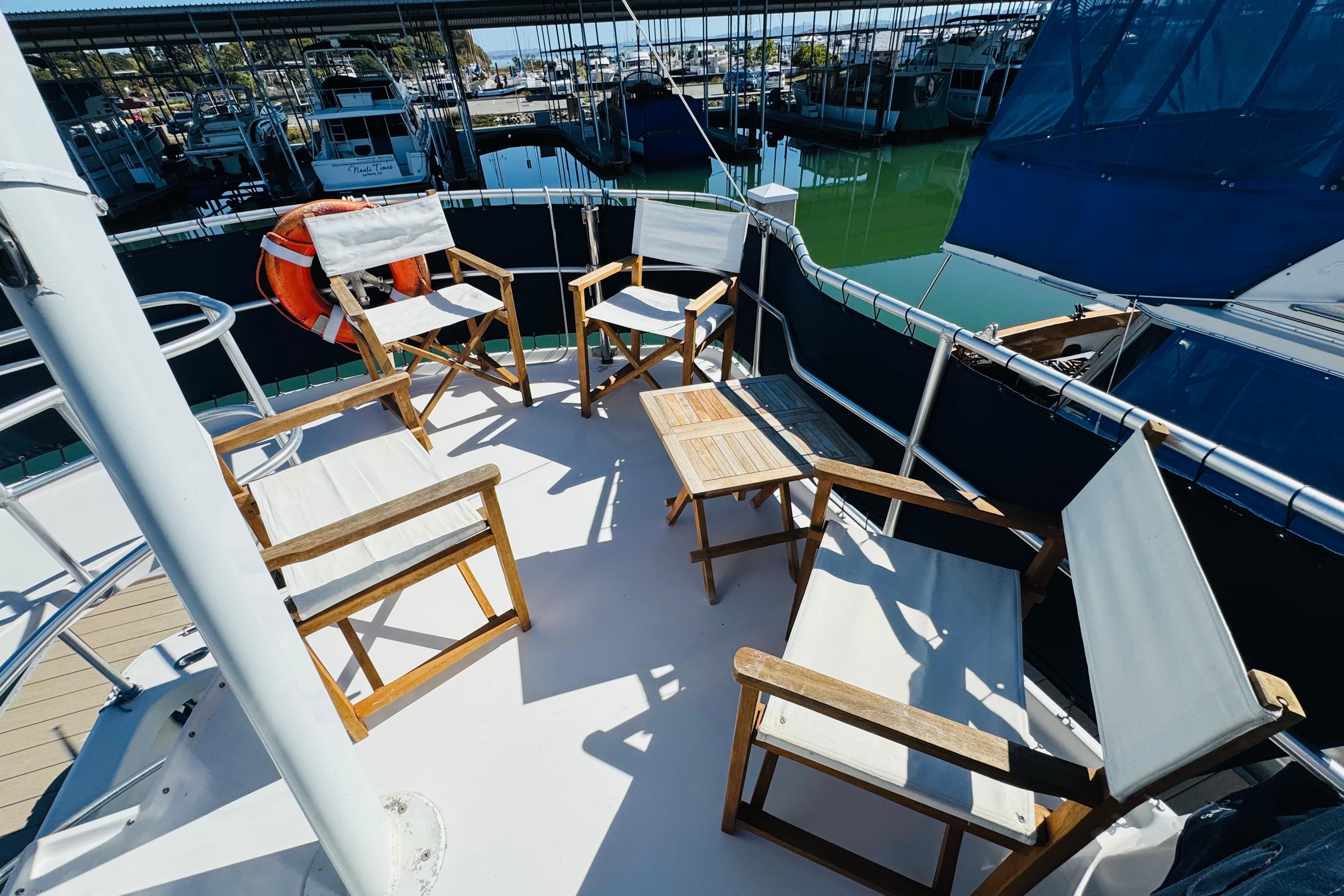 Deck of 2000 Mainship 390 Trawler with chairs and table, docked at marina.