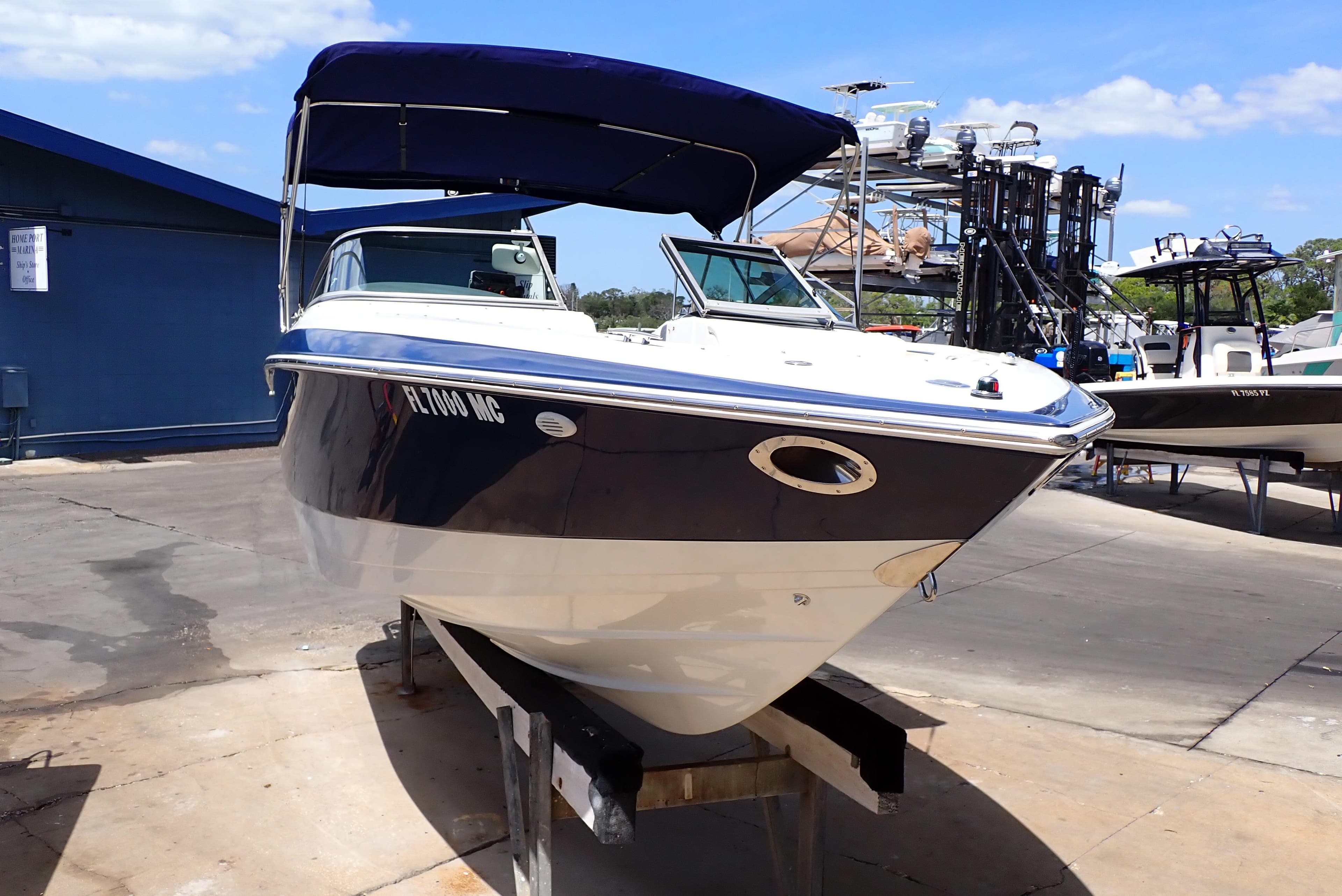 2002 Cobalt 240 boat with blue canopy on a dock under clear skies.