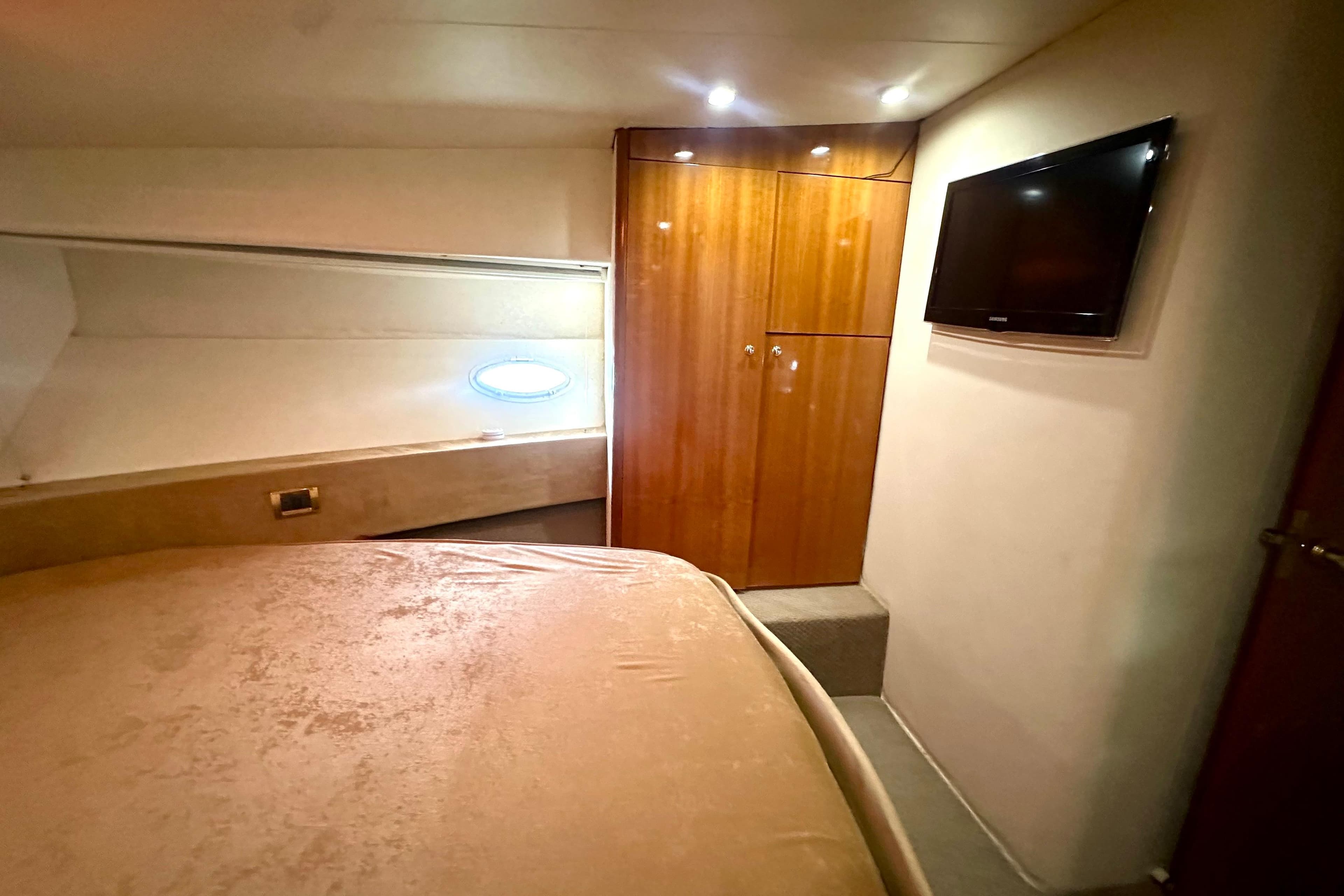 Luxurious cabin interior of a 1999 Azimut 58 yacht with TV and wooden cabinetry.