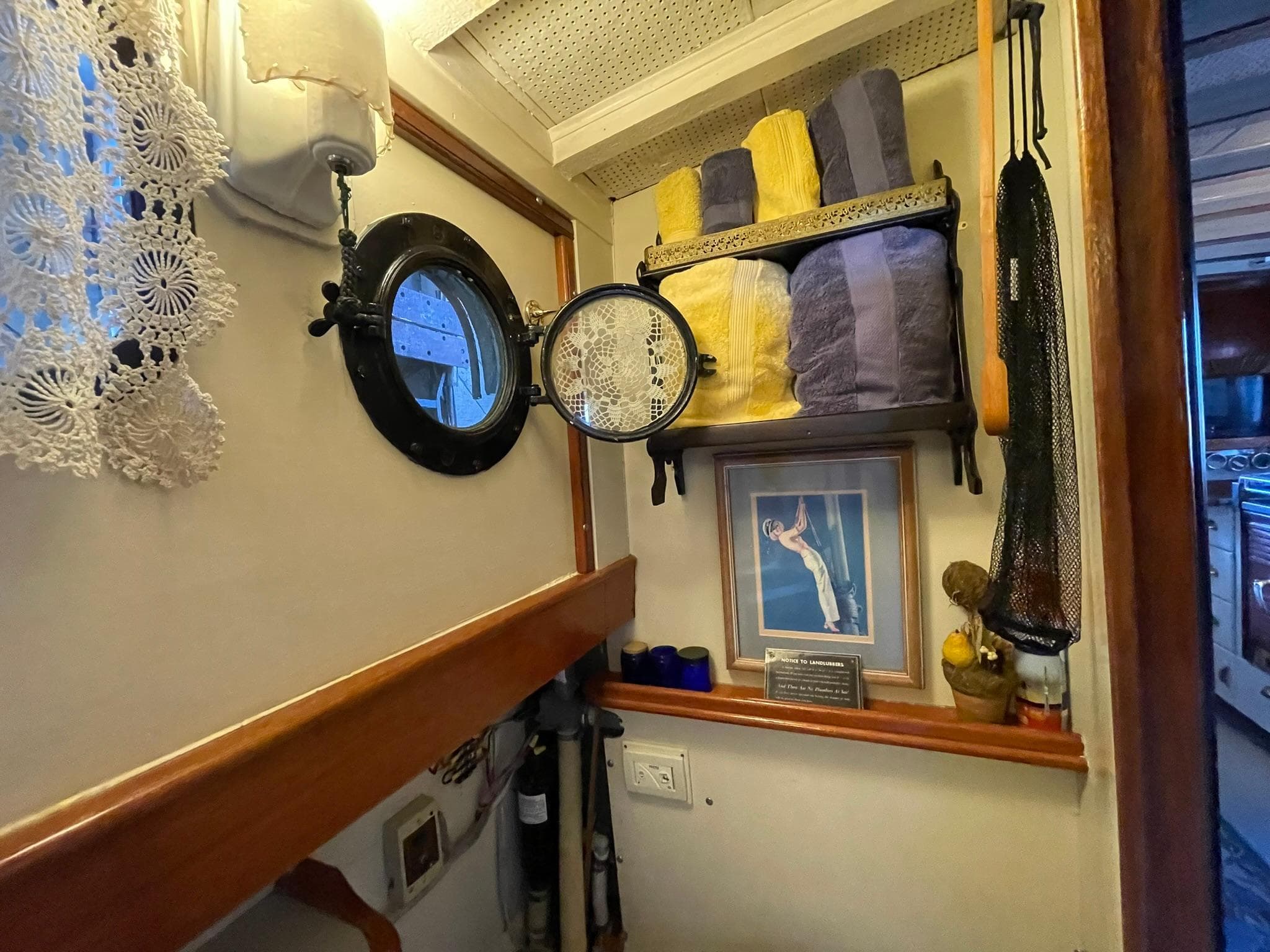 1940 Historic Tacoma Boat Co Cruiser interior with porthole, towels, and framed artwork.