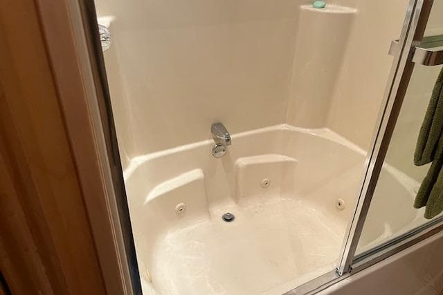 Compact shower area in 2008 Fantasy Houseboat with white fixtures and glass door.