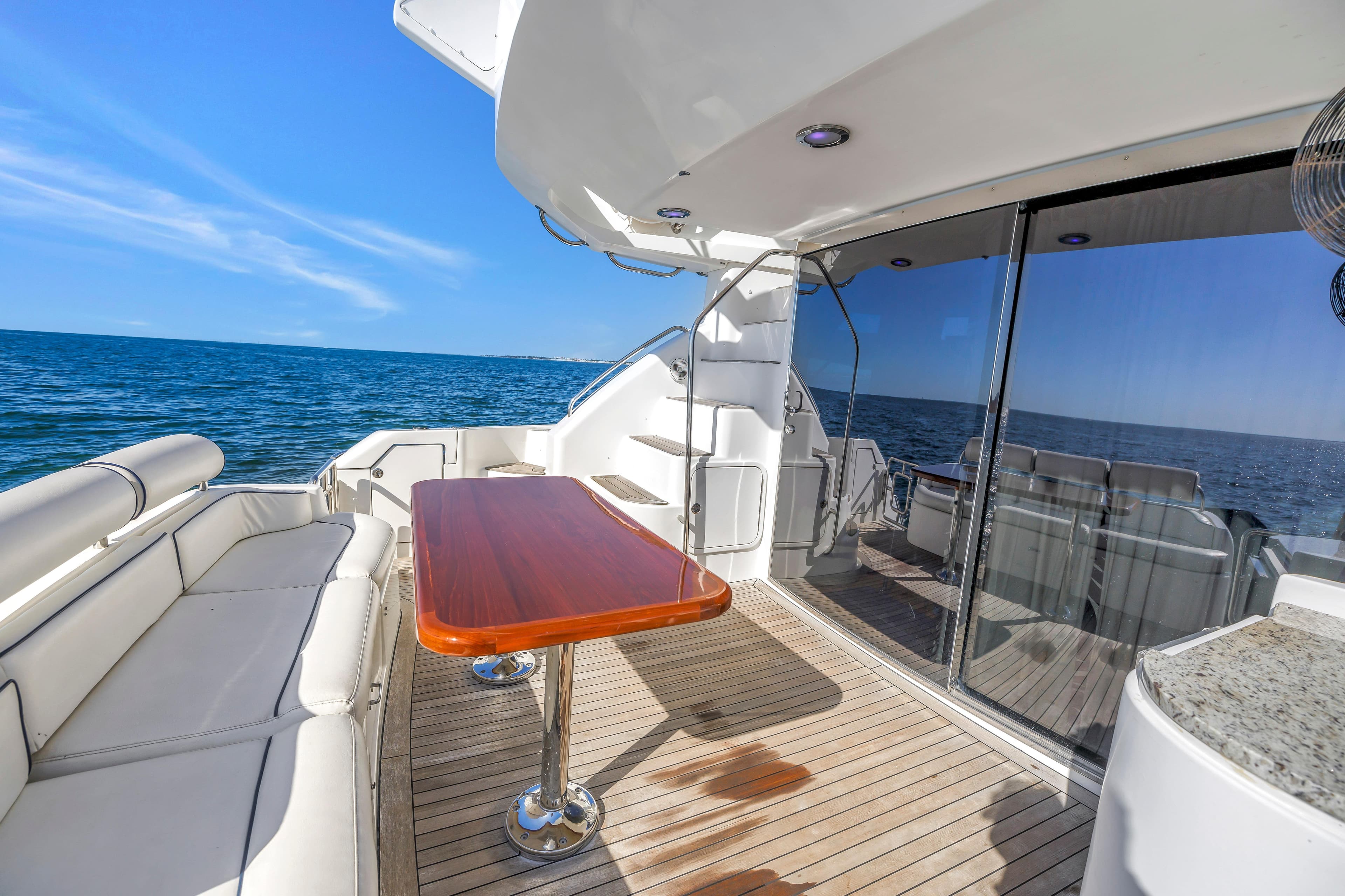 Luxurious Neptunus 56 Flybridge yacht deck with ocean view, featuring elegant seating and table.