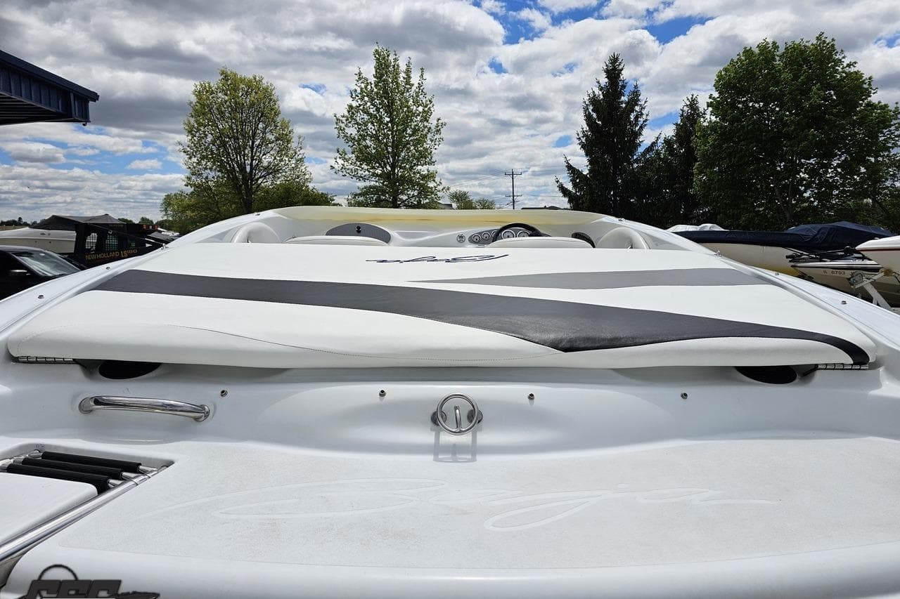 2004 Baja H2X boat with sleek white and black design, parked outdoors under cloudy sky.
