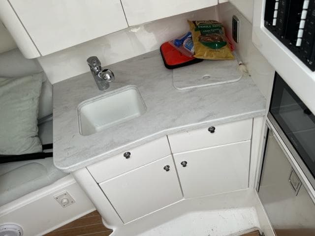 Compact kitchen area in a 2018 Intrepid 375 Walkaround boat with sink and storage cabinets.