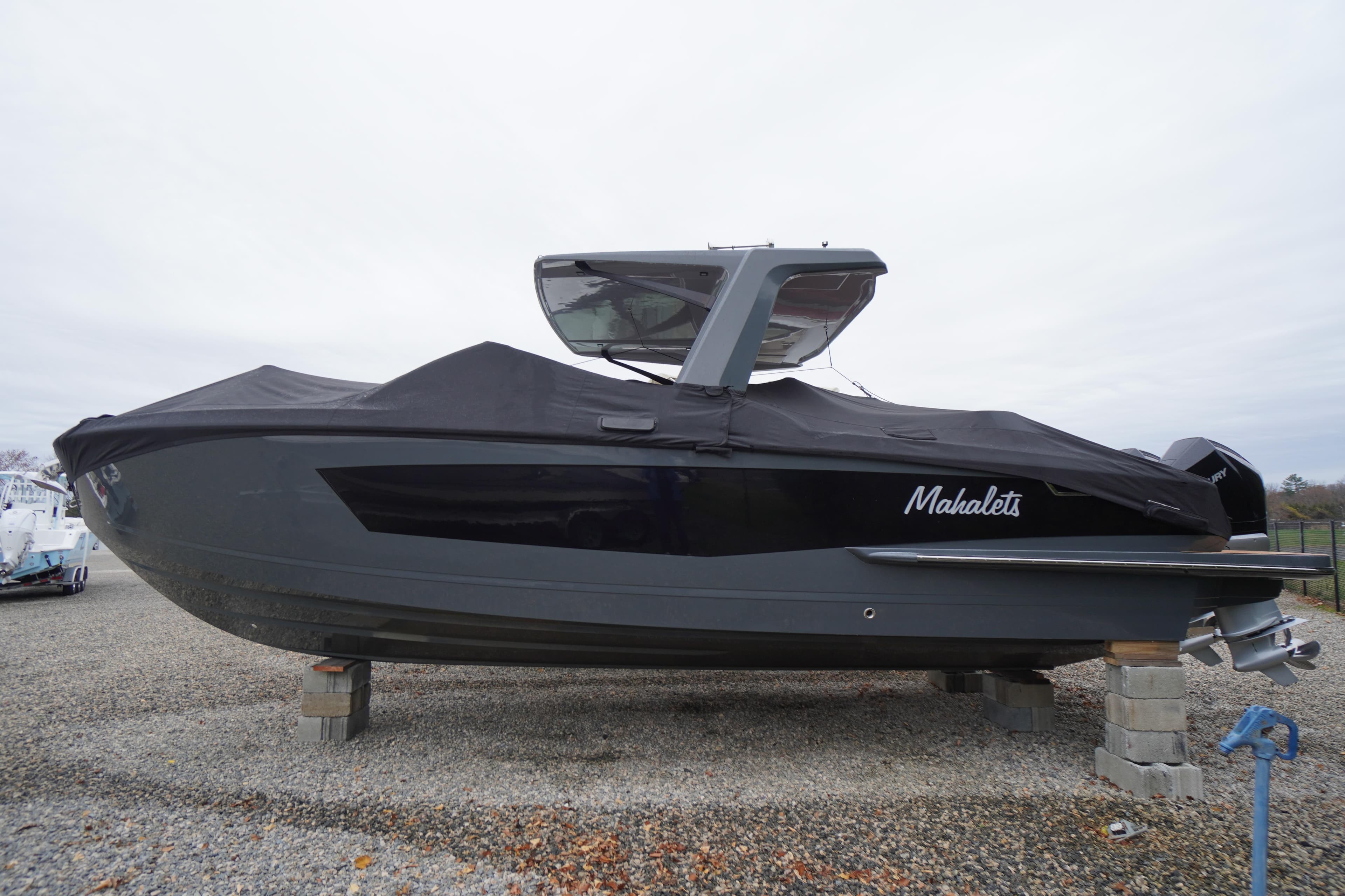 2020 Aviara AV32 OB boat covered and elevated on blocks, side view.
