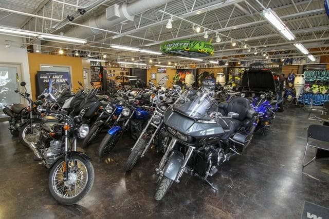 Showroom filled with various motorcycles and gear, featuring a 2024 Robalo 206 Cayman.