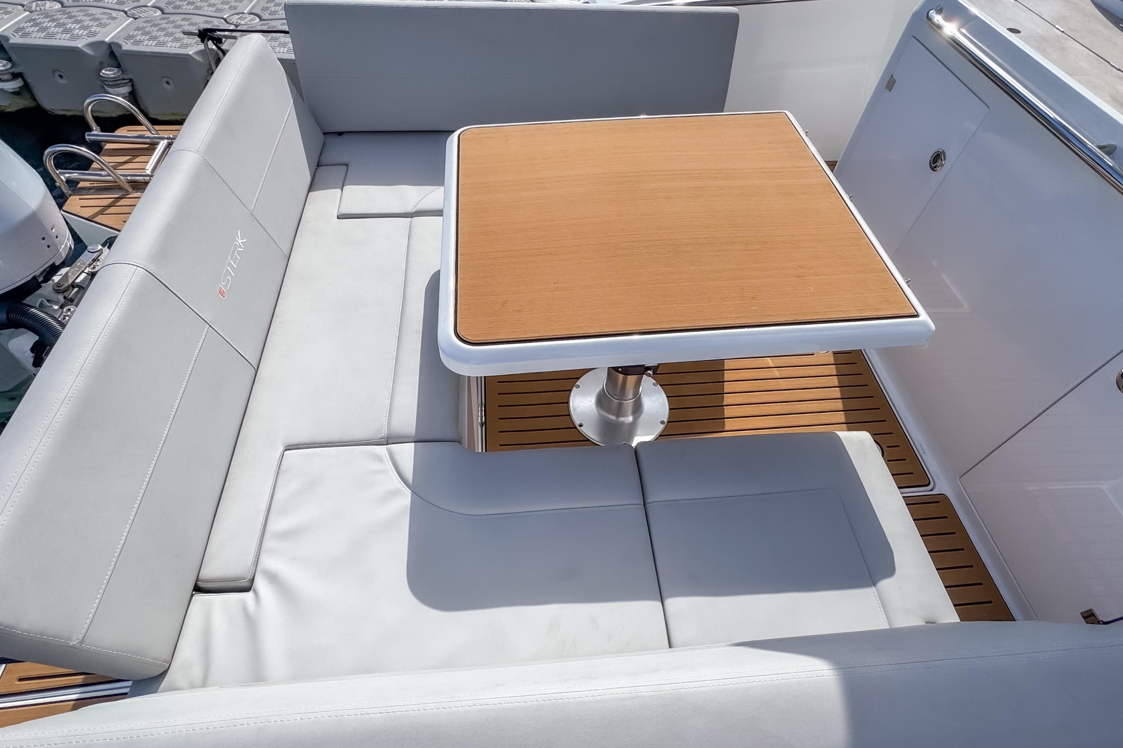Luxurious seating area on 2025 STERK 31 boat with wooden table and cushioned seats.