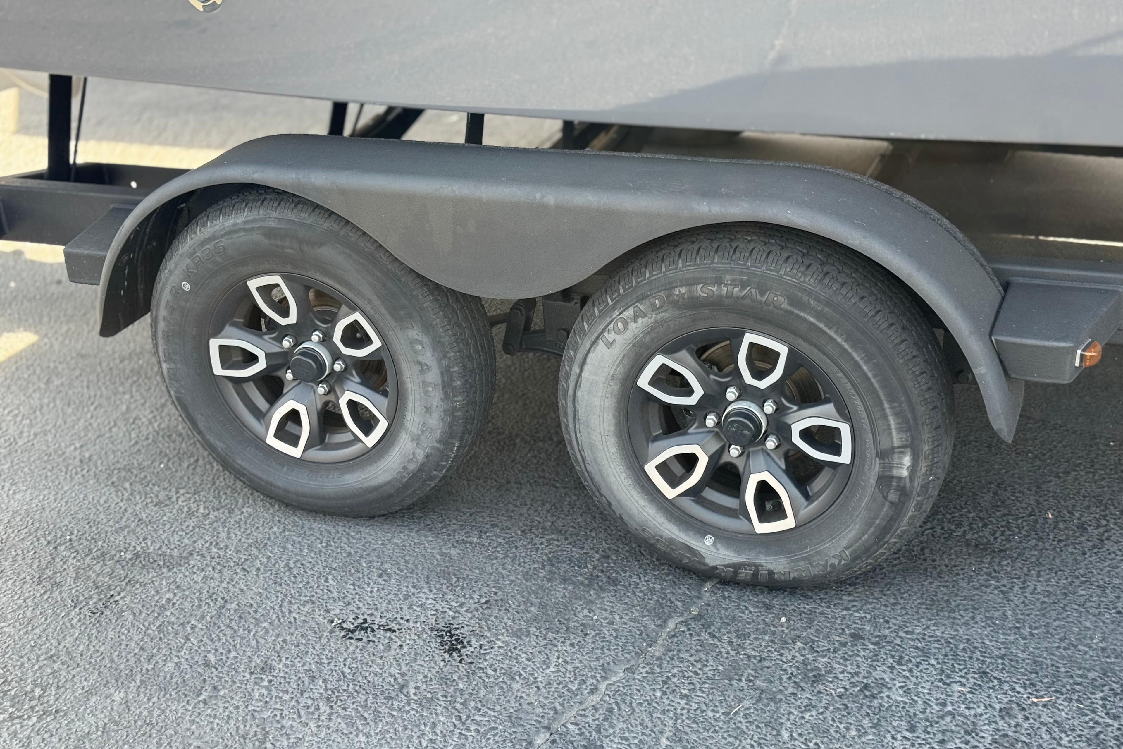 Trailer wheels of a 2023 Four Winns HD3 boat on pavement.