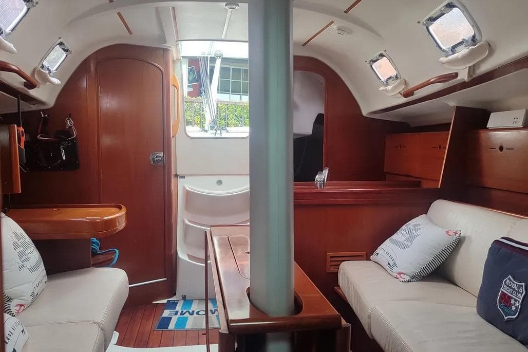 Interior of 2000 Beneteau First 31.7 sailboat with cozy seating and wooden finishes.