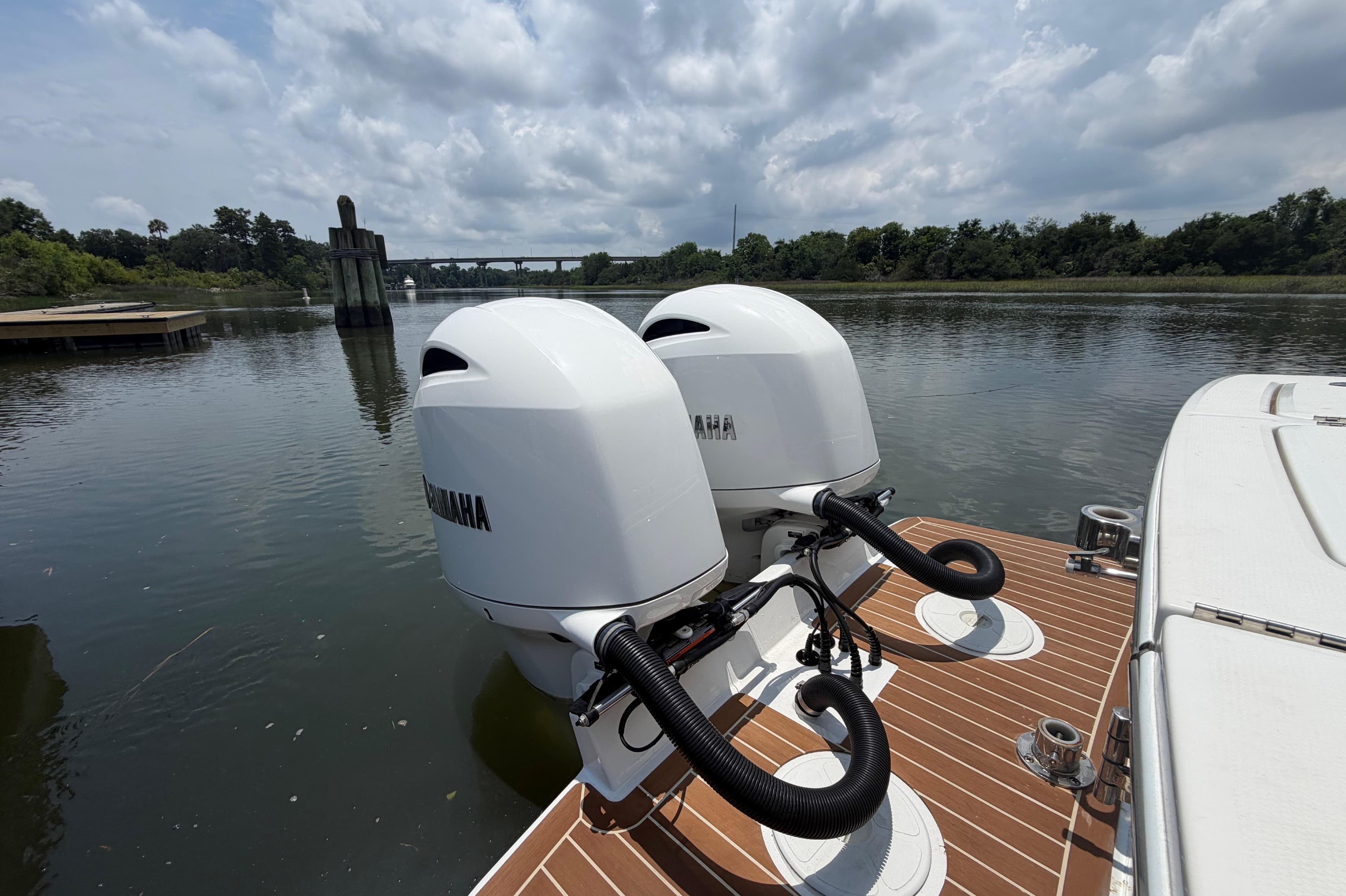 Twin Yamaha outboard engines on a 2022 Regulator 23 boat, docked on a calm river.