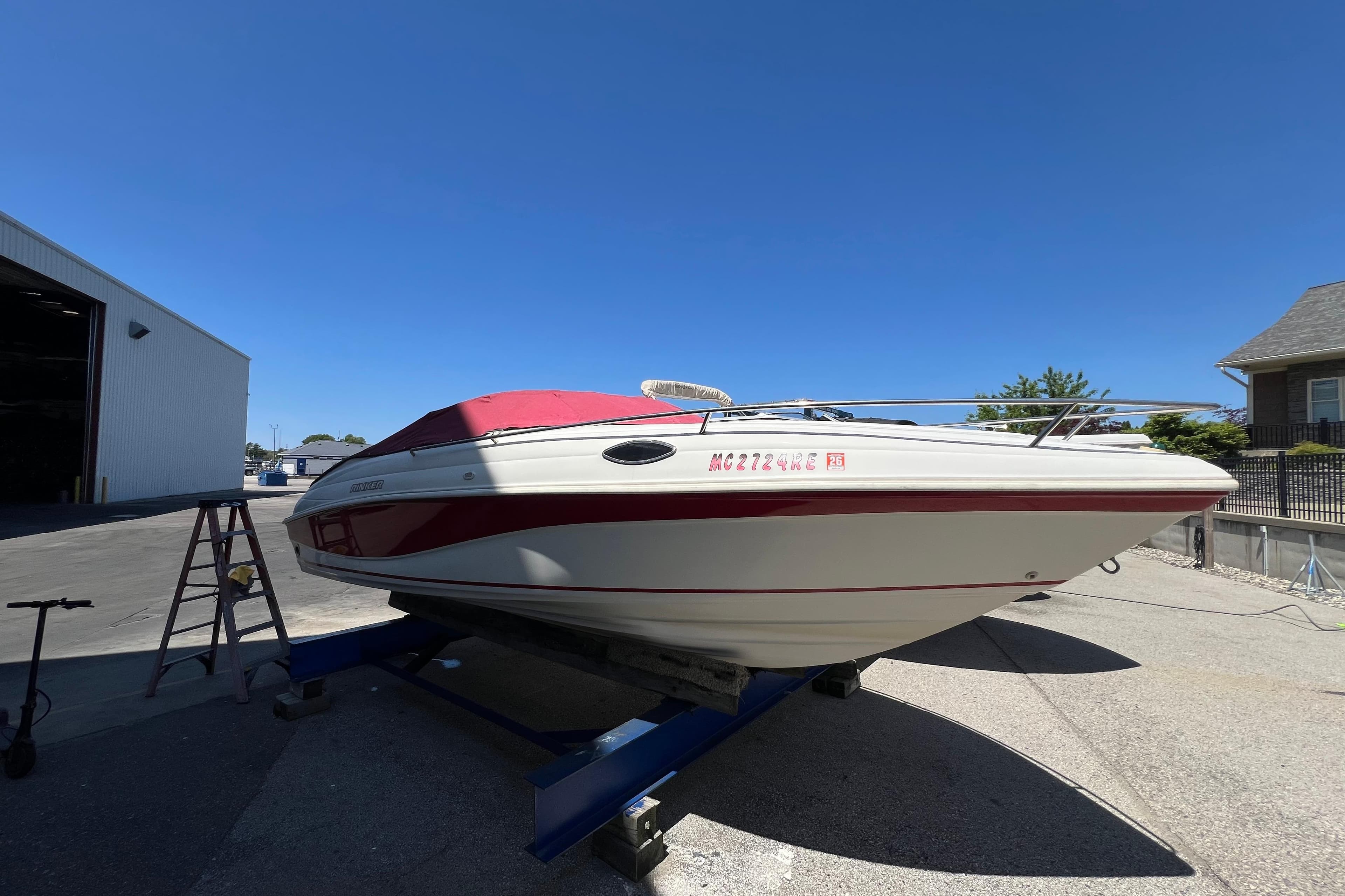 1996 Rinker 232 Captiva Cuddy boat on trailer, red and white design, sunny day.