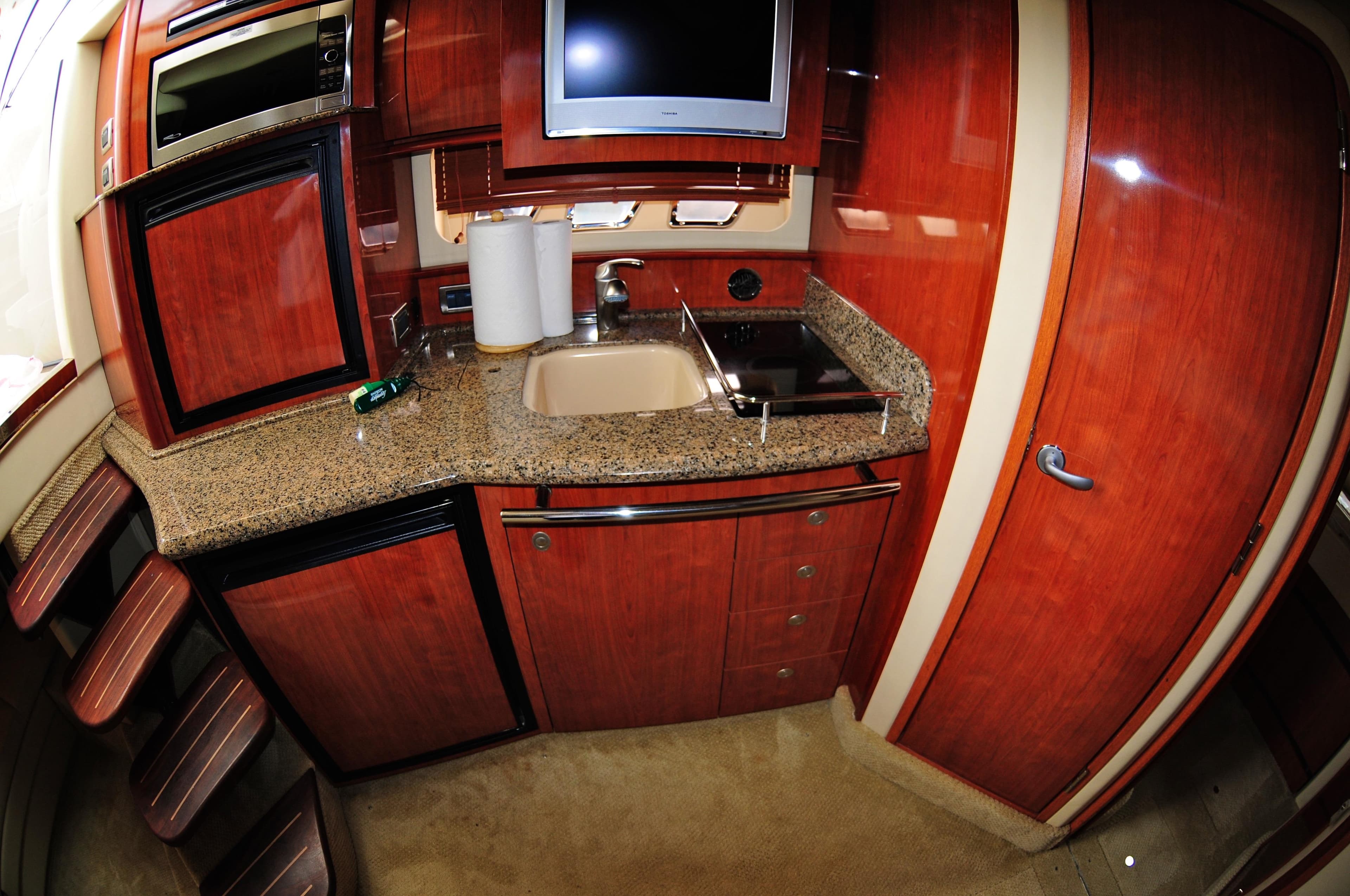 Luxurious kitchen interior of 2006 Sea Ray 380 Sundancer yacht with wood cabinetry.
